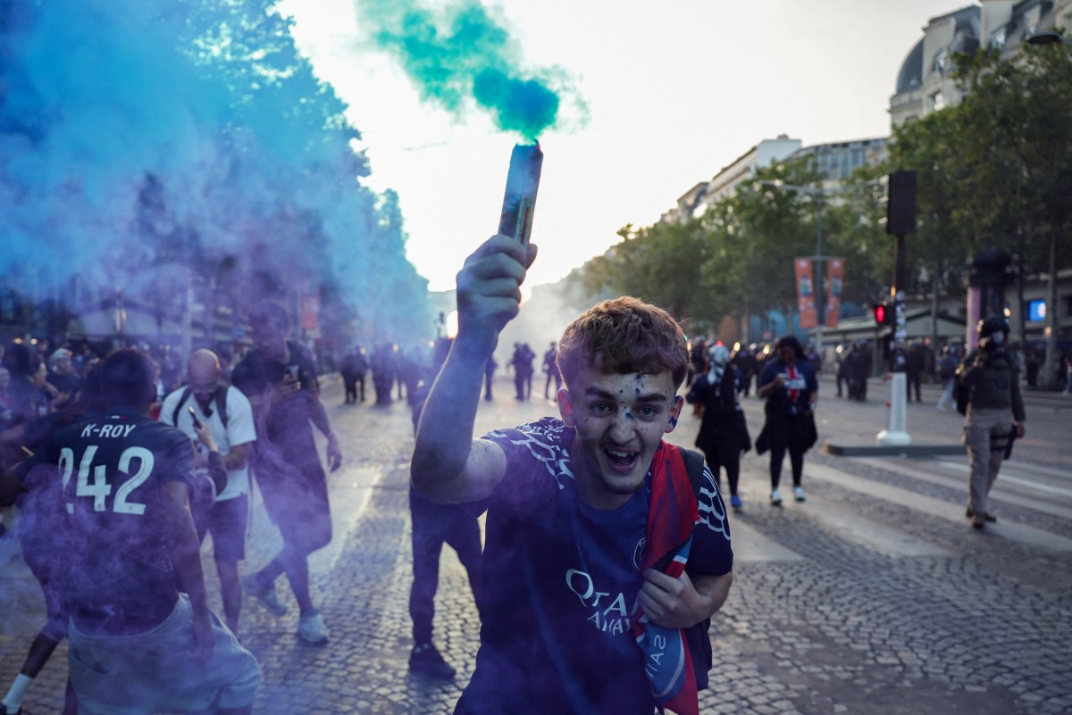 PSG supporters celebrate on the Champs-Elysees Avenue after their team's win in the UEFA Champions League final football match between Paris Saint-Germain (PSG) and Arsenal