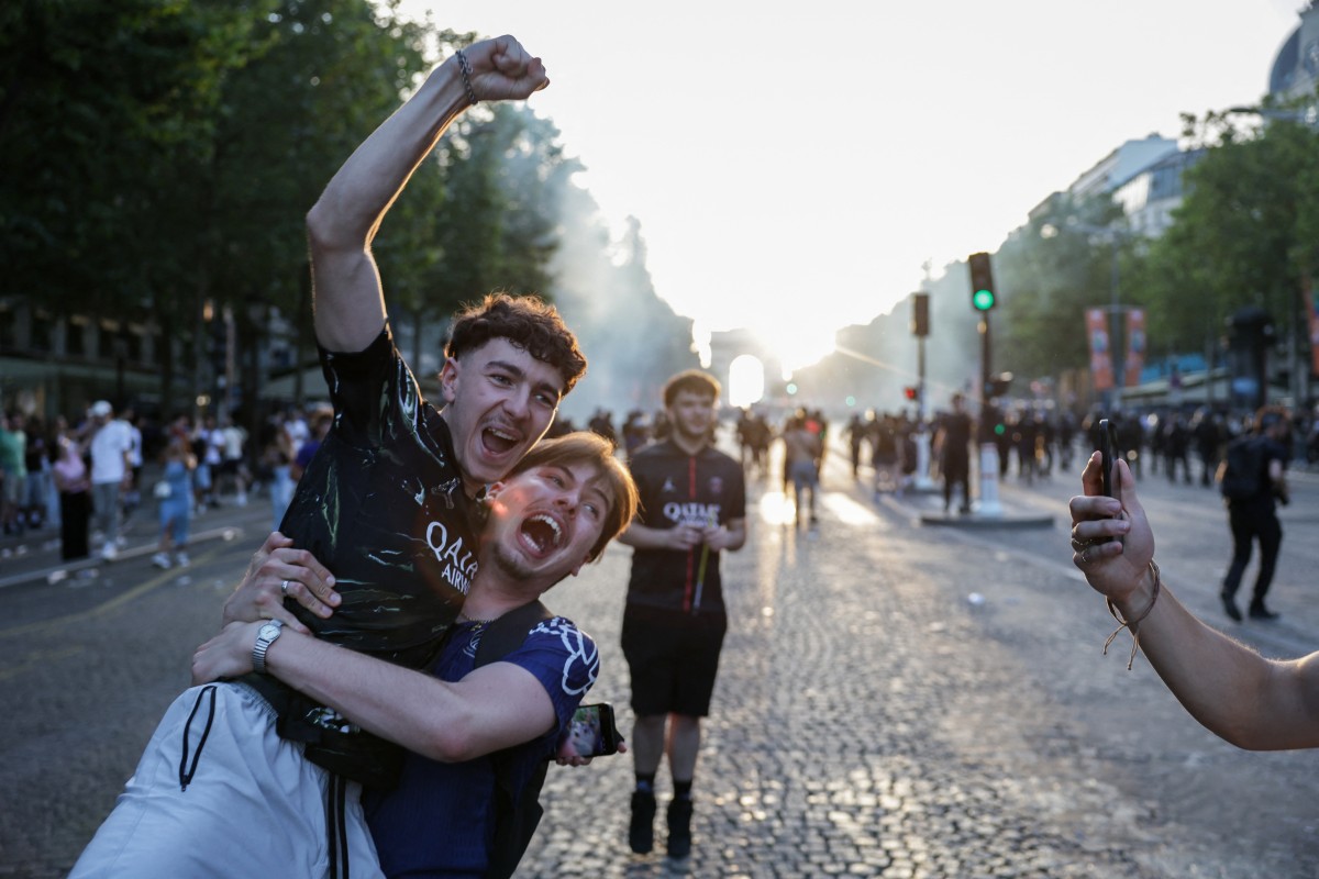 PSG supporters celebrate on the Champs-Elysees Avenue after their team's win in the UEFA Champions League final football match between Paris Saint-Germain (PSG) and Arsenal