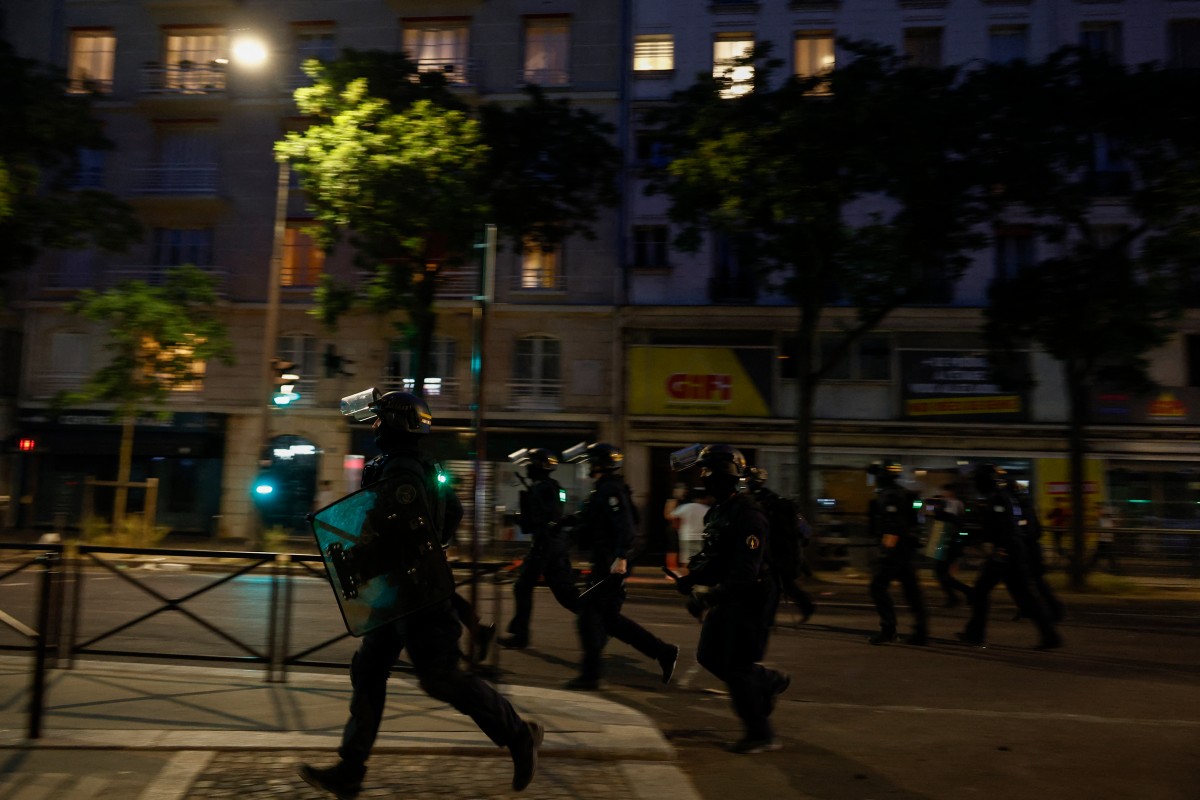 French Republican Security Corps (CRS - Compagnies Republicaines de Securite) Police officers run on a street to disperse PSG supporters during celebrations following their team's win in the UEFA Champions League final