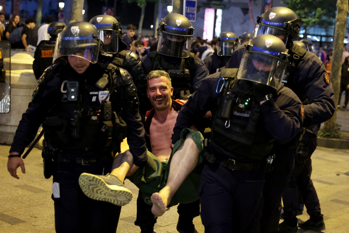 French Republican Security Corps (CRS - Compagnies Republicaines de Securite) Police officers detain a PSG supporter during celebrations following their team's win in the UEFA Champions League final 