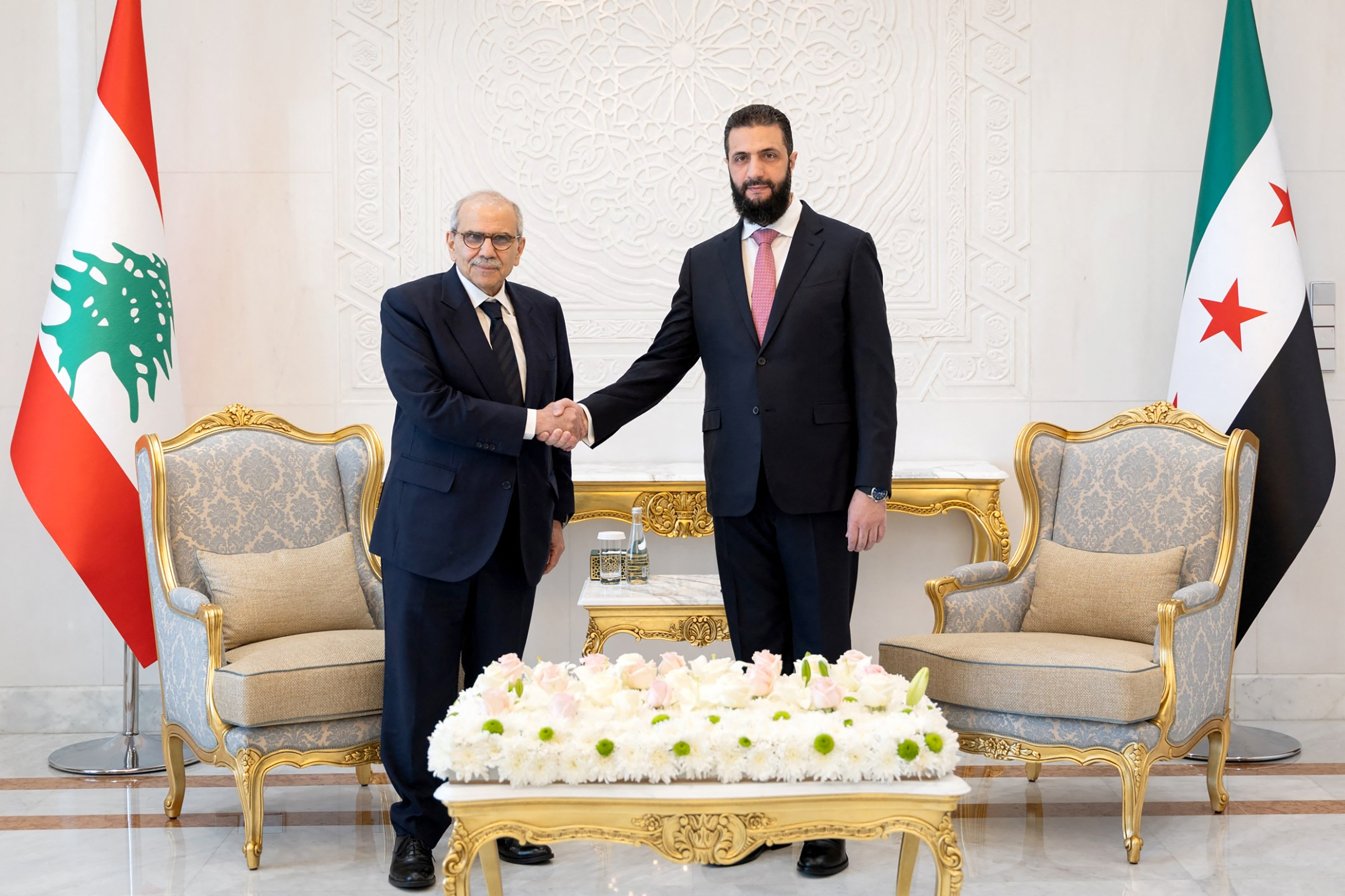 Syrian President Ahmed al-Sharaa shakes hands with Lebanese Prime Minister Nawaf Salam at the People's Palace in Damascus