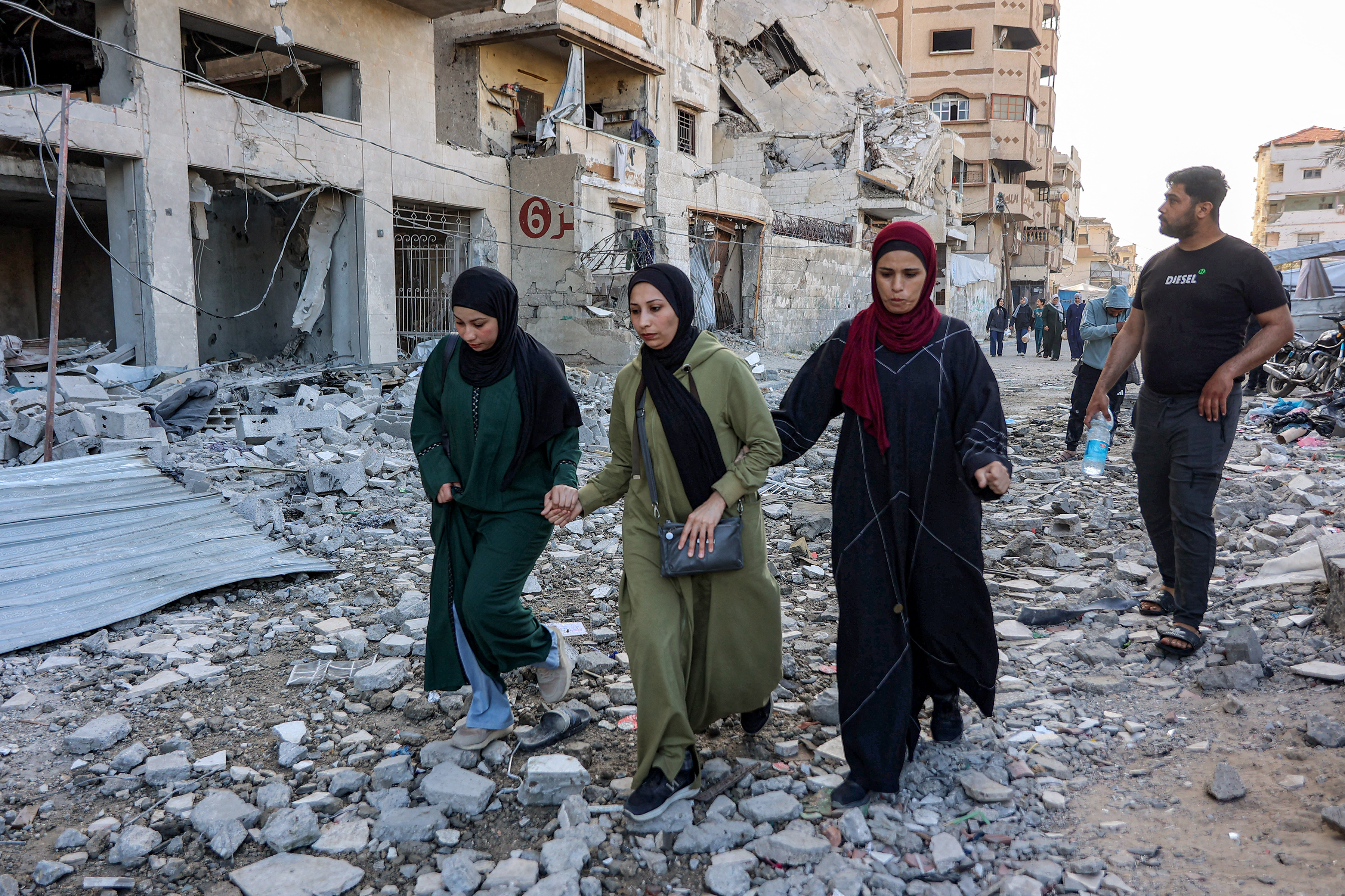 People walk outside a residential building that was hit by an Israeli strike the previous day in the Rimal neighbourhood of Gaza City on May 16, 2026.