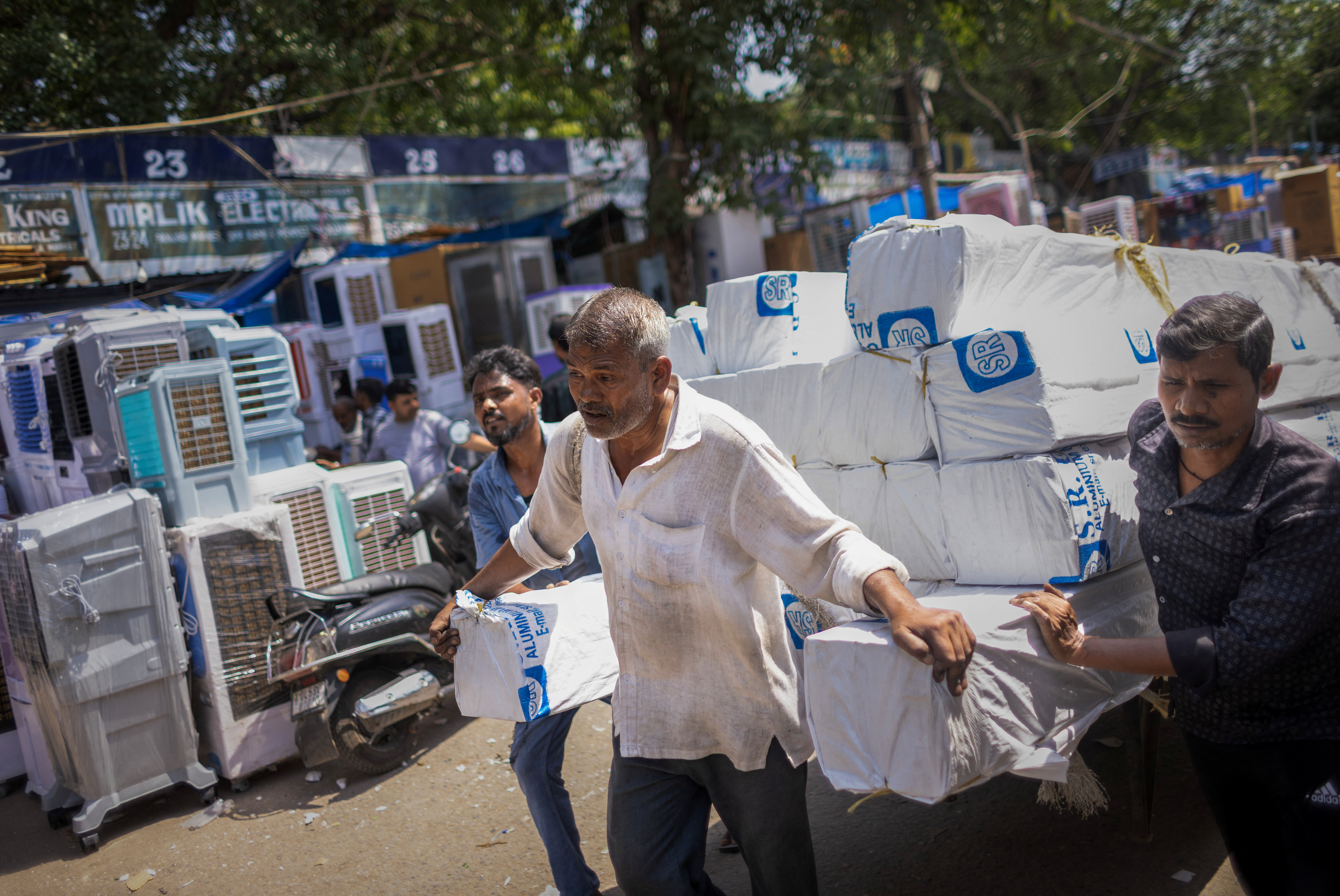 Labourers use a cart to transport aluminium pipes at a market on a hot summer day in New Delhi, India, April 29, 2026. REUTERS/Adnan Abidi