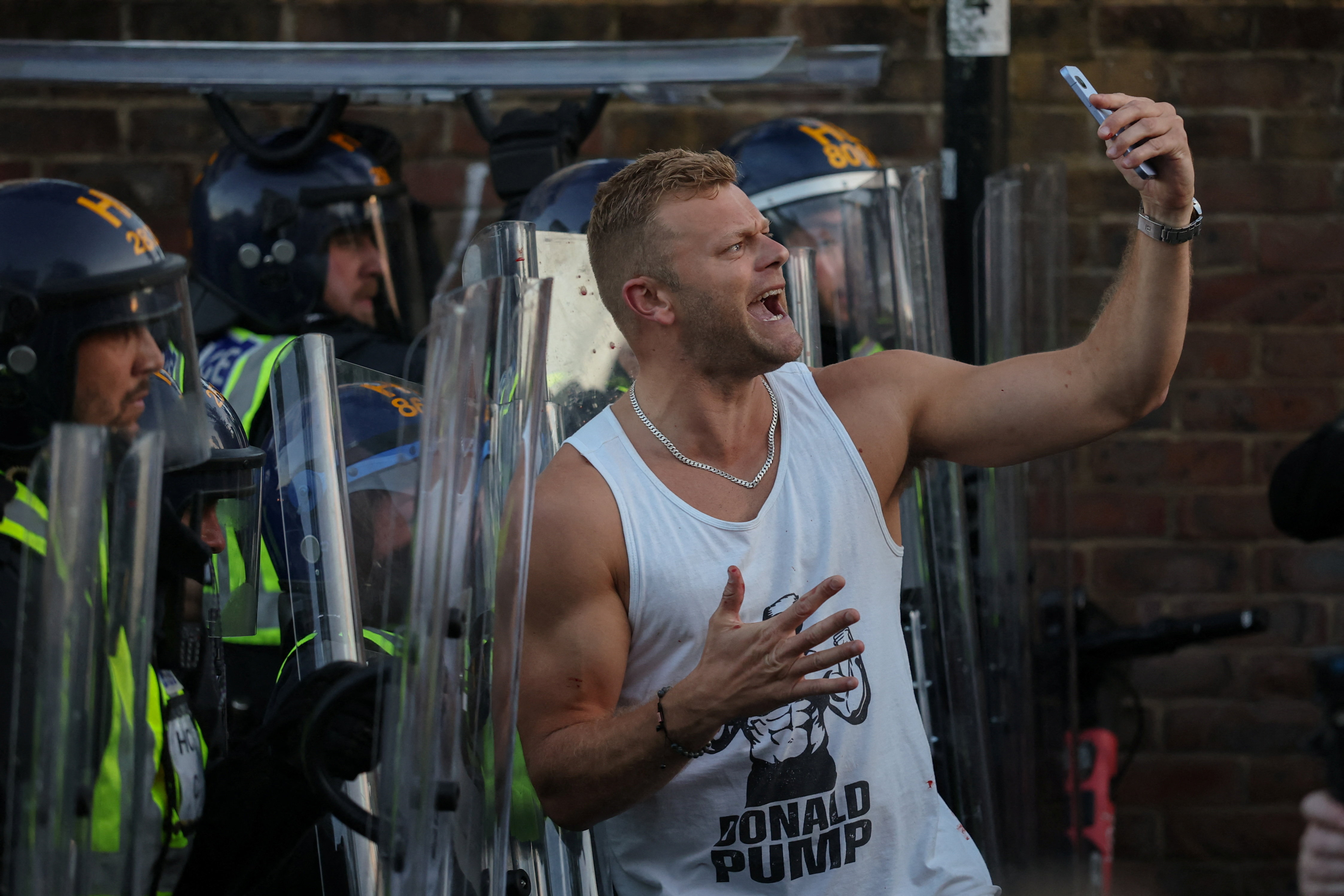A protester holds a mobile phone as he stands in front of police officers during a demonstration following the conviction of Vikrum Digwa for the murder of student Henry Nowak, in Southampton, Britain, June 2, 2026. REUTERS/Isabel Infantes