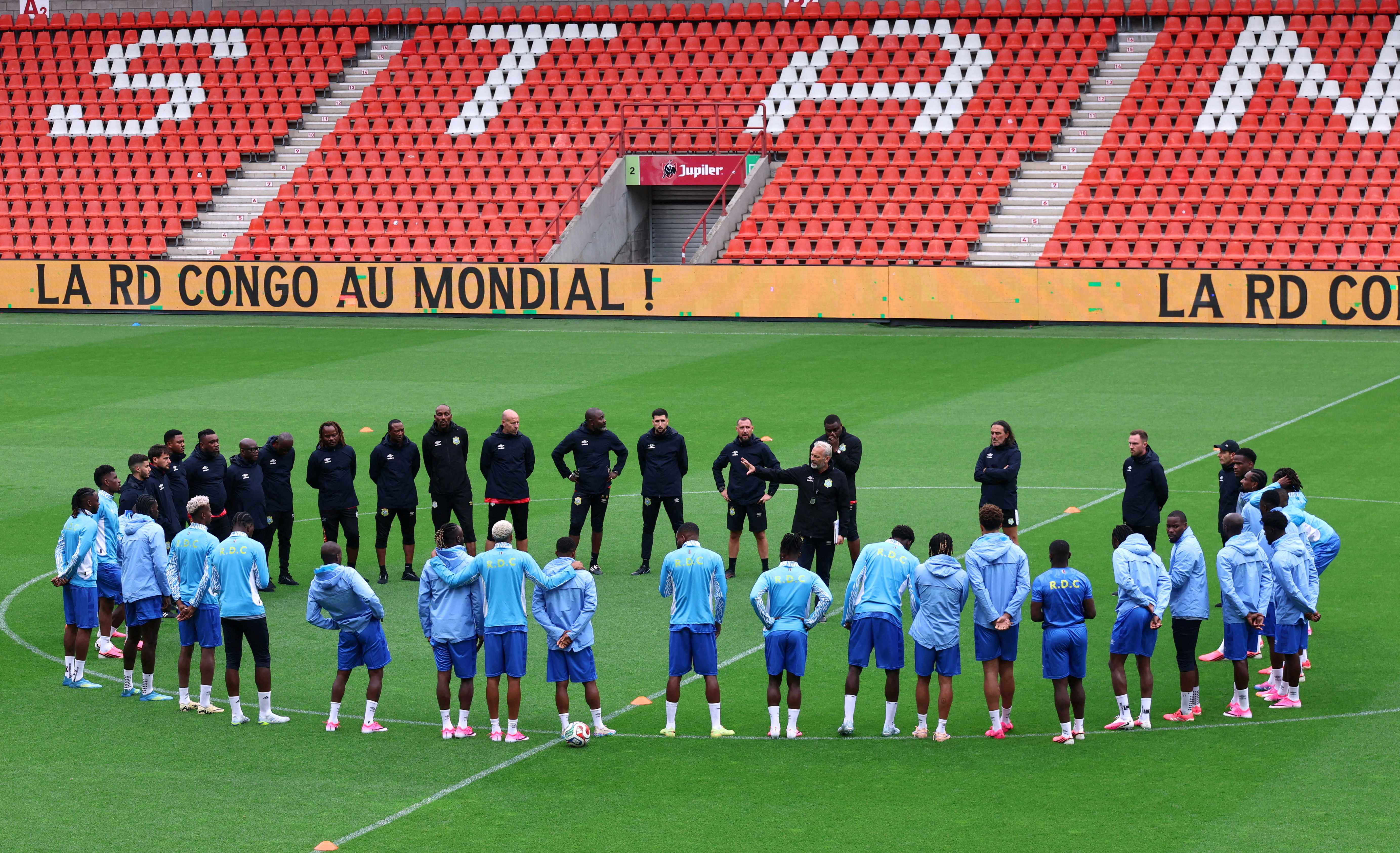 DRC players and staff stand in a circle on a football pitch