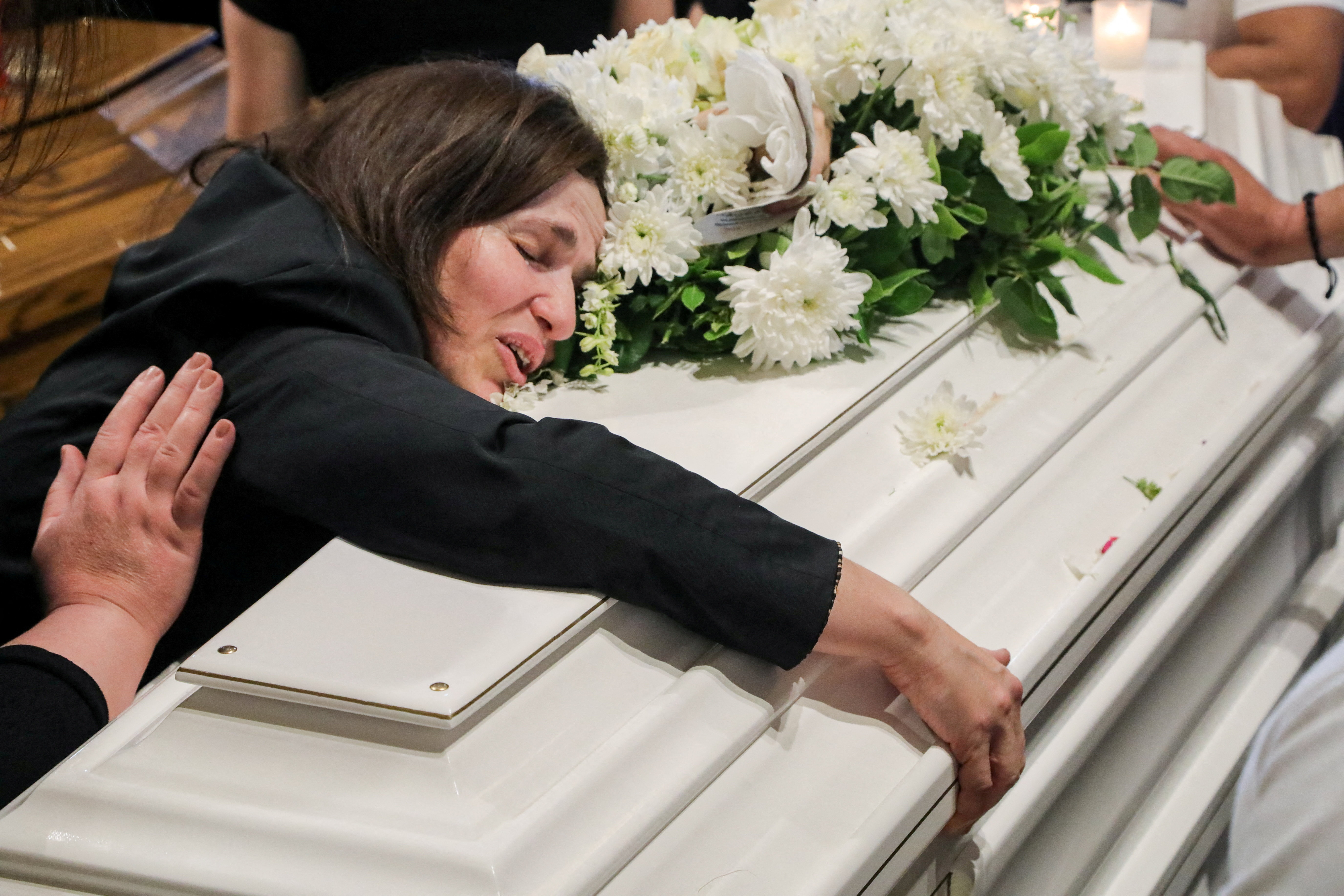 A mourner leans over a coffin at the funeral of dentist James George Karam and his children, Theodosia and Tony, who were killed in an Israeli strike, in Qlayaa, Lebanon June 3, 2026. REUTERS/Stringer TPX IMAGES OF THE DAY