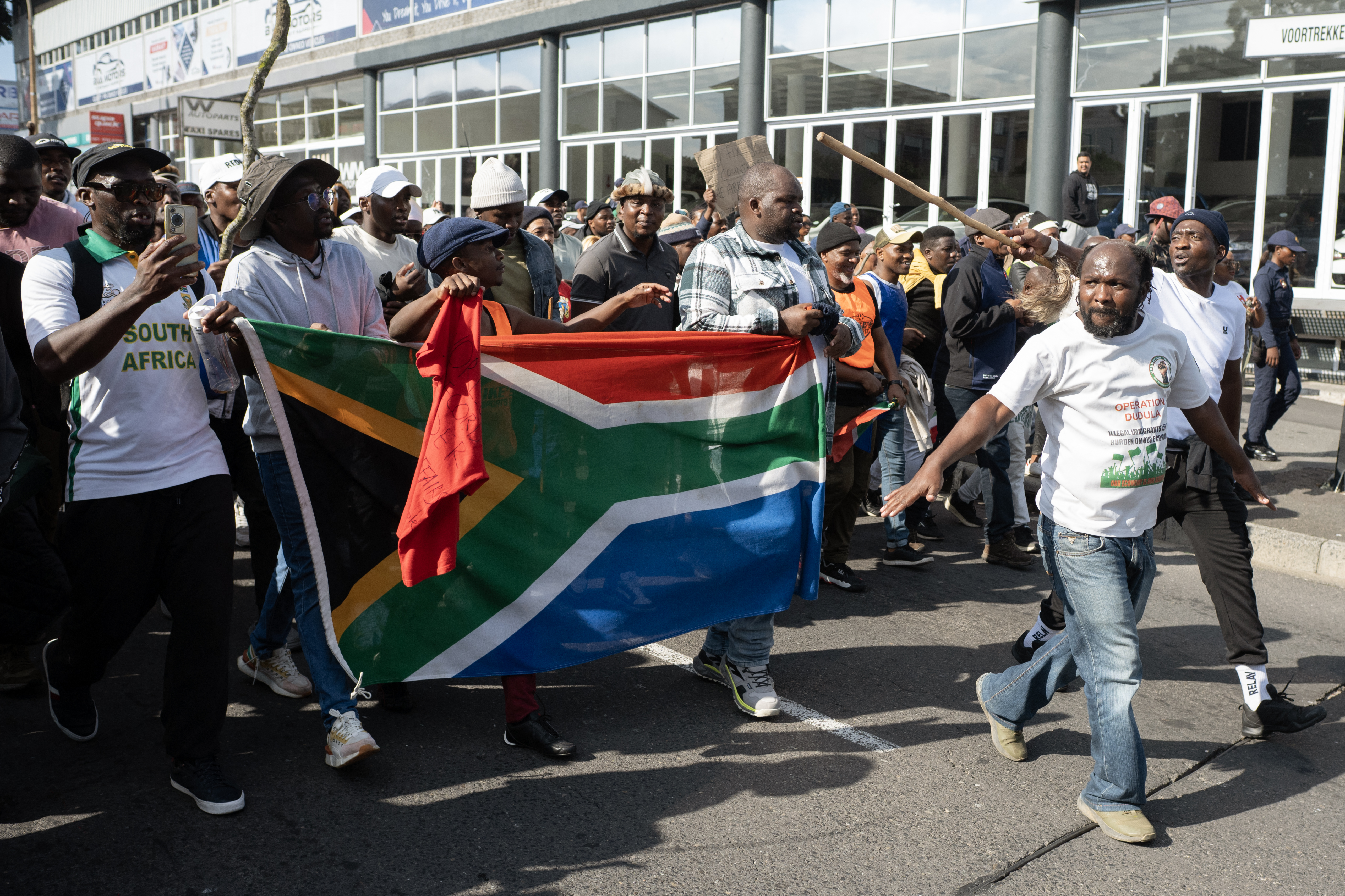 Demonstrators hold a South African flag as they march.