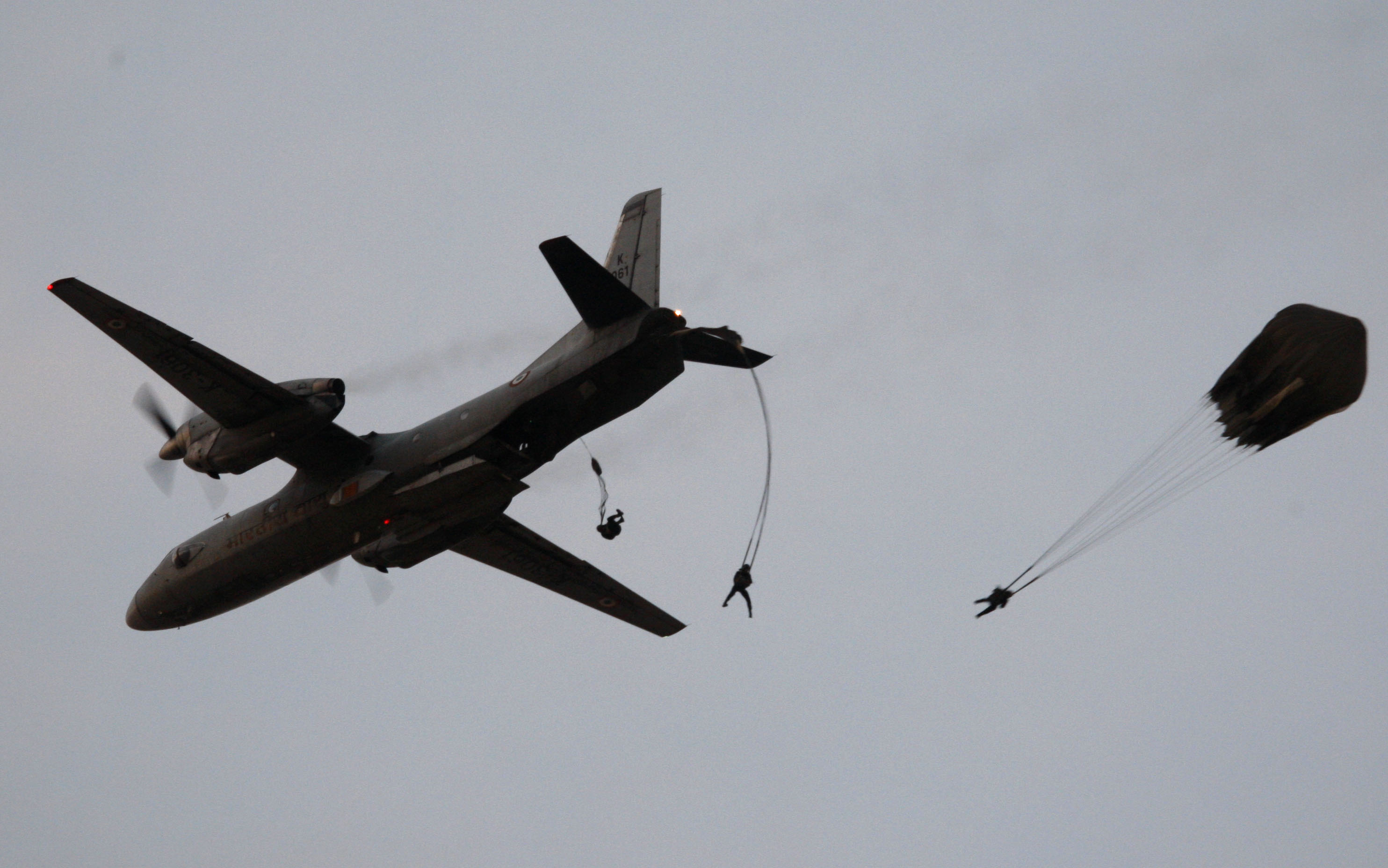 Paratroopers jump from an aircraft.