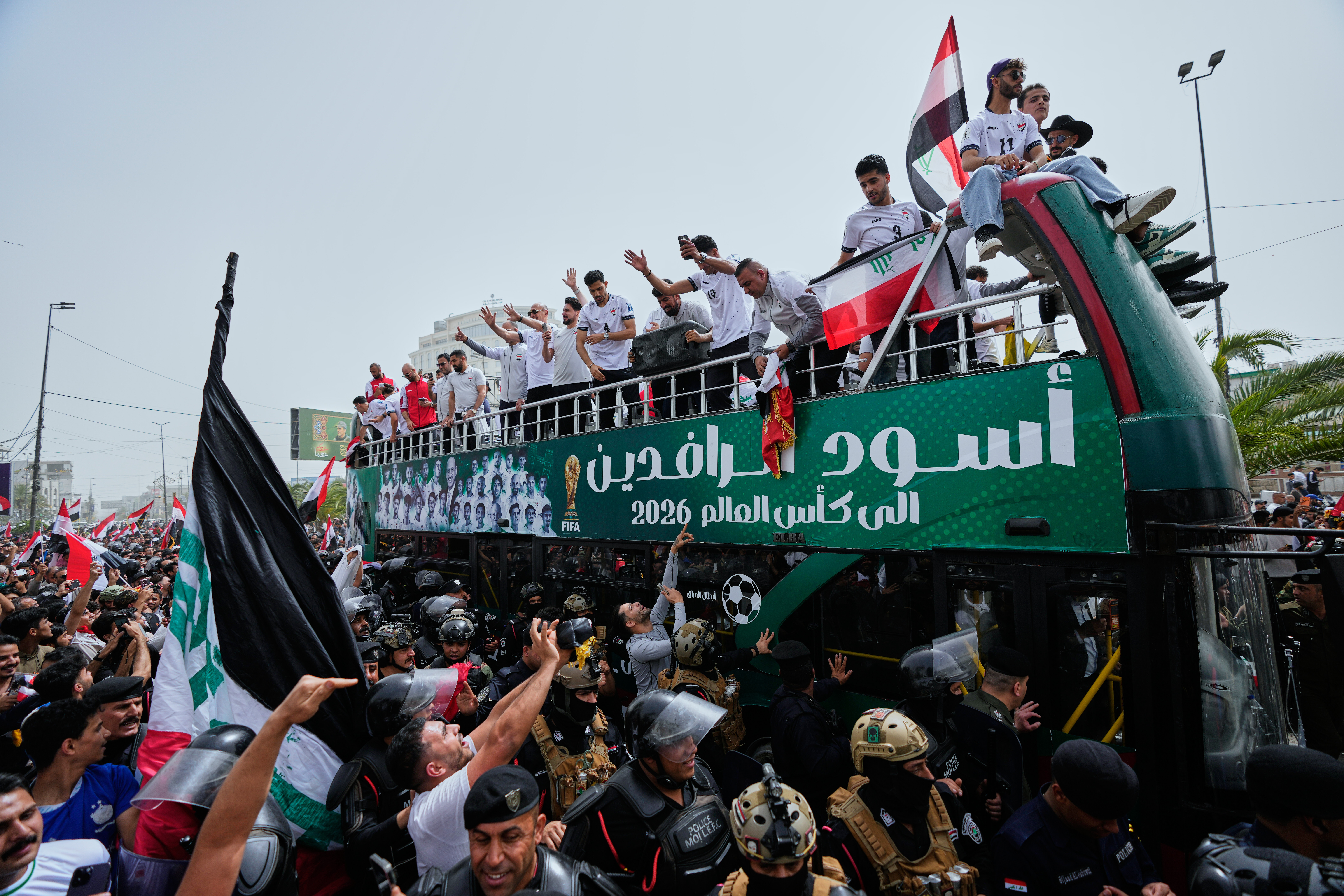 Iraq's soccer players celebrate with fans during an open-top bus procession and ceremony after qualifying for the 2026 World Cup in central Baghdad, Iraq, Saturday, April 4, 2026. (AP Photo/Hadi Mizban)