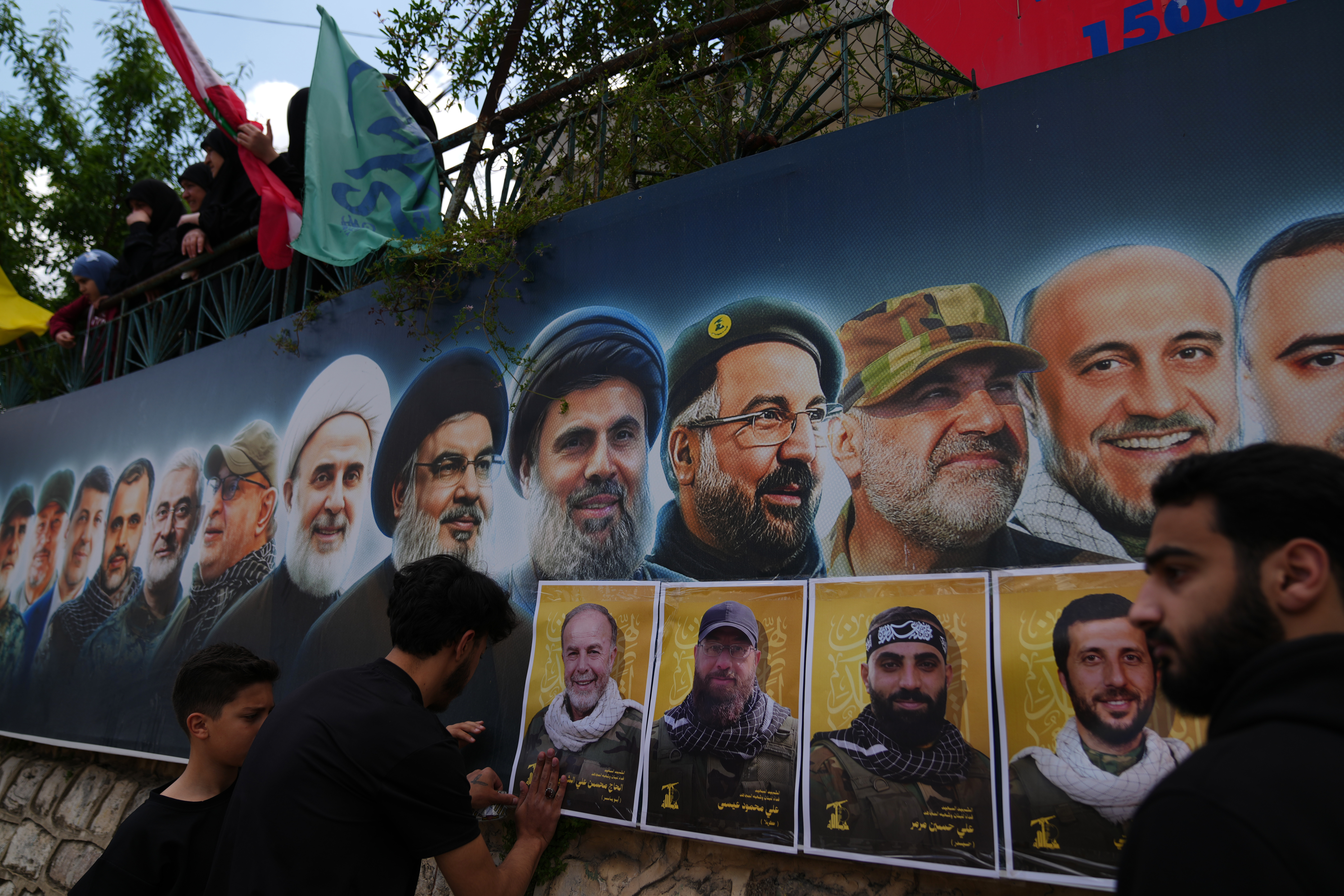 Hezbollah supporters hang portraits of Hezbollah fighters killed in Israeli airstrikes during their funeral procession in the southern village of Kfar Sir, Lebanon, on Tuesday, April 21, 2026. (AP Photo/Hassan Ammar)