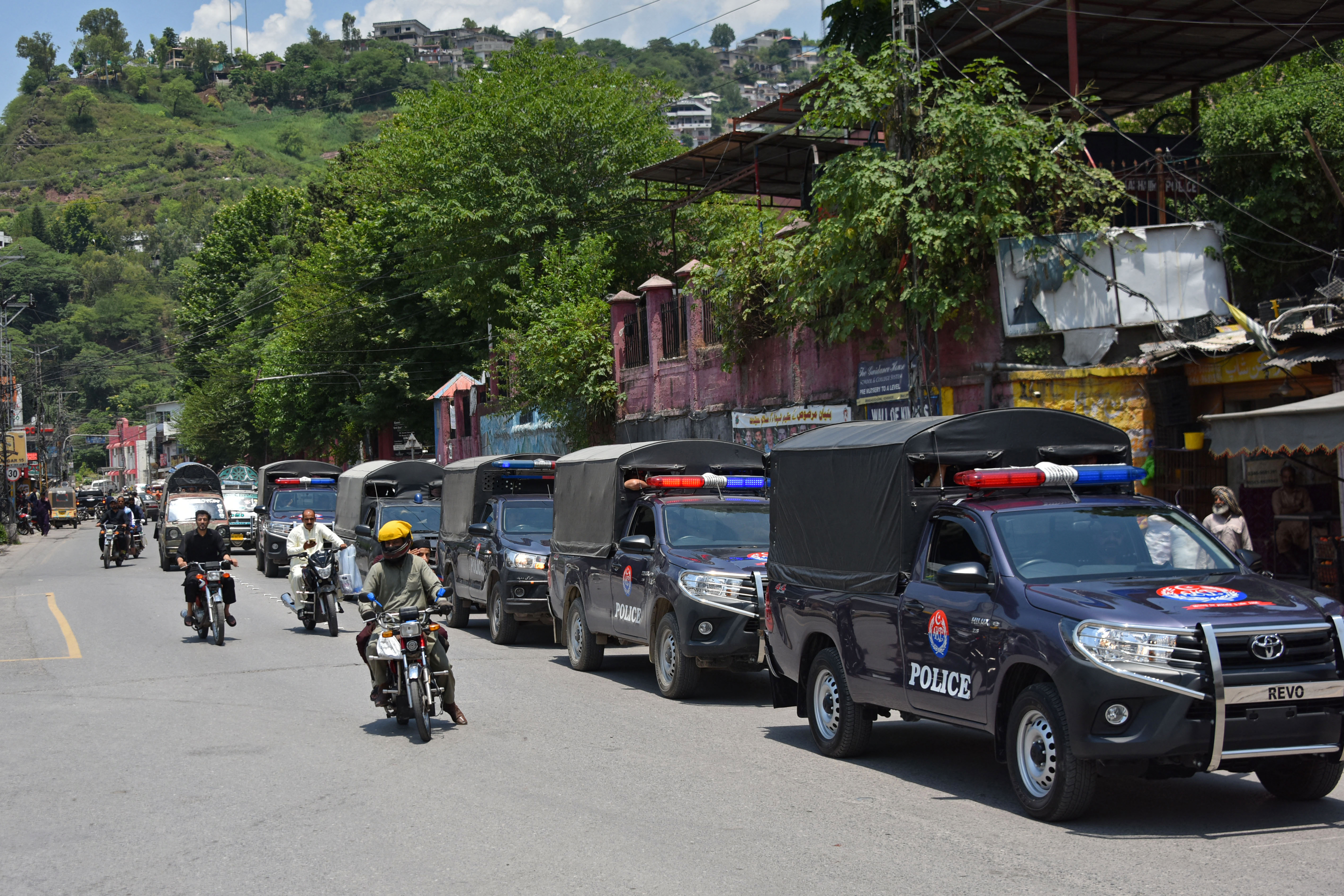 Commuters ride past security personnel as they patrol a street.