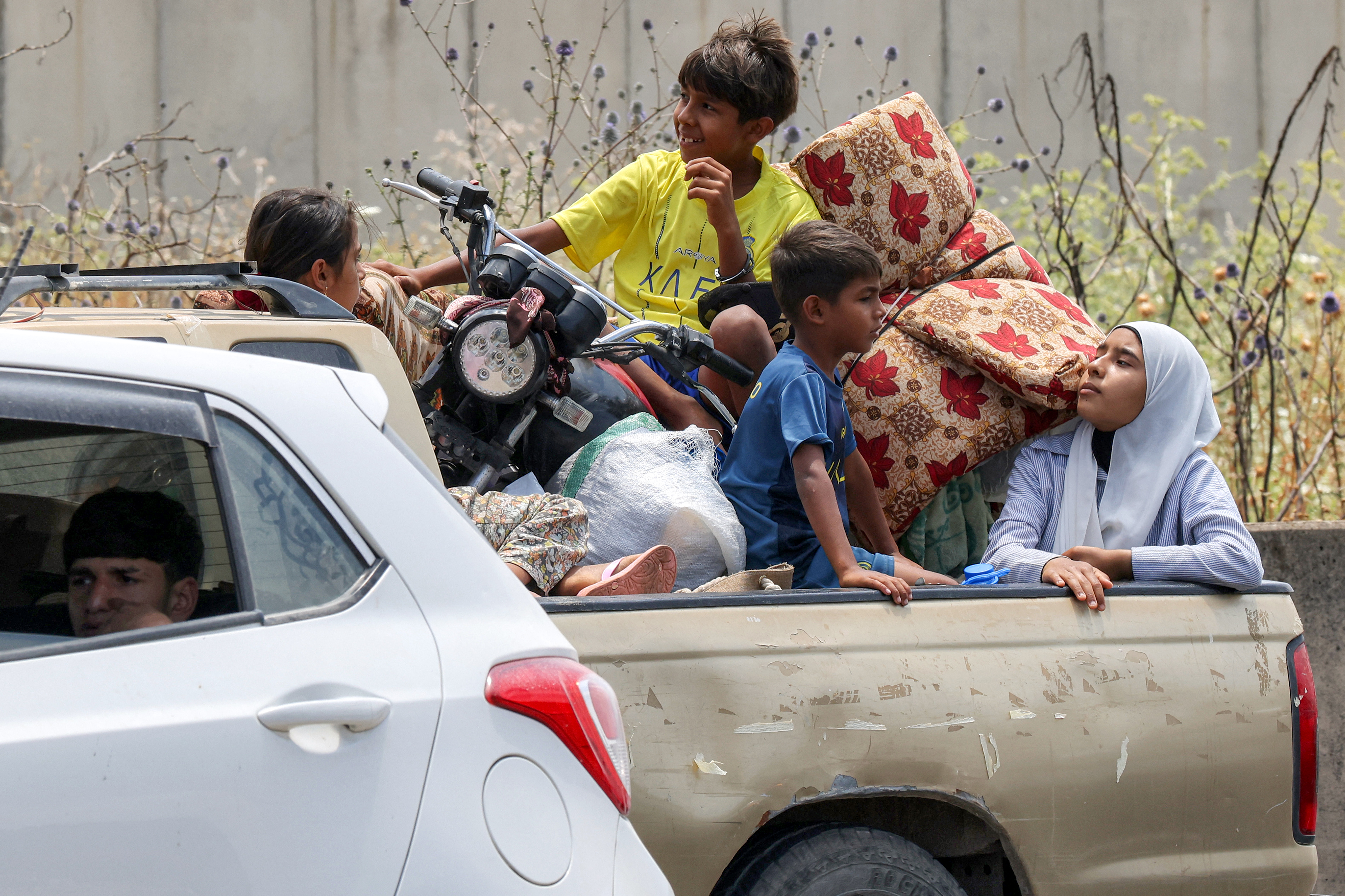 Children sit in the bed of a pickup truck waiting in traffic, as people fleeing from Tyre in southern Lebanon after Israel's evacuation warning seek refuge in more northerly Sidon, on June 9, 2026.