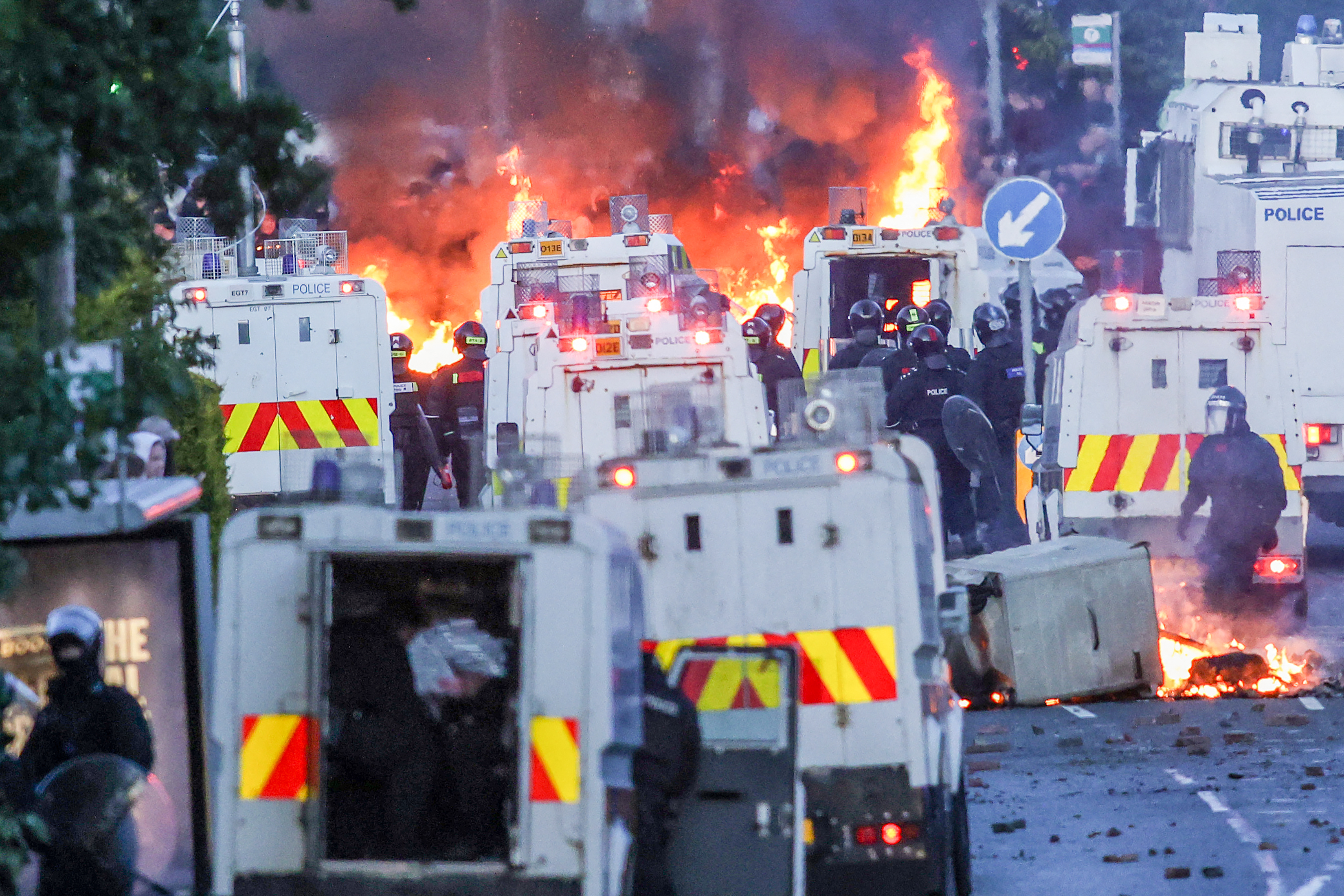 Fires burn around police vehicles as protesters (behind) stand off with police in Glengormley, north of Belfast, Northern Ireland, on June 10, 2026.