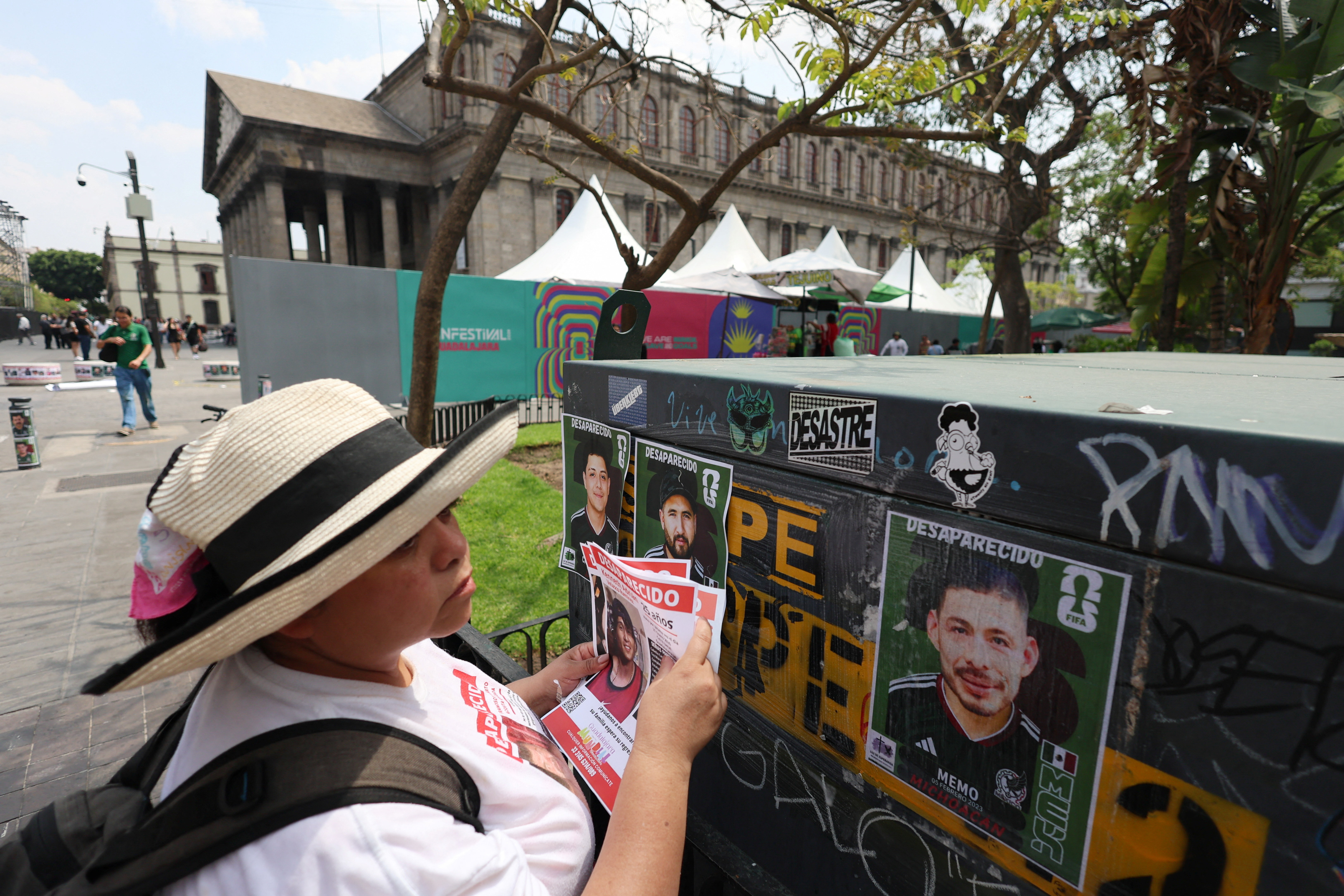 A member of the Colectivo Luz de Esperanza de Jalisco collective holds missing-person flyers near pasted signs featuring images of their loved ones who remain missing, displayed in a World Cup-style format, as part of the “Missing Persons World Cup Album" campaign to raise awareness of disappearances ahead of the 2026 FIFA World Cup, in Guadalajara, Mexico, May 31, 2026.  REUTERS/Michelle Freyria TPX IMAGES OF THE DAY