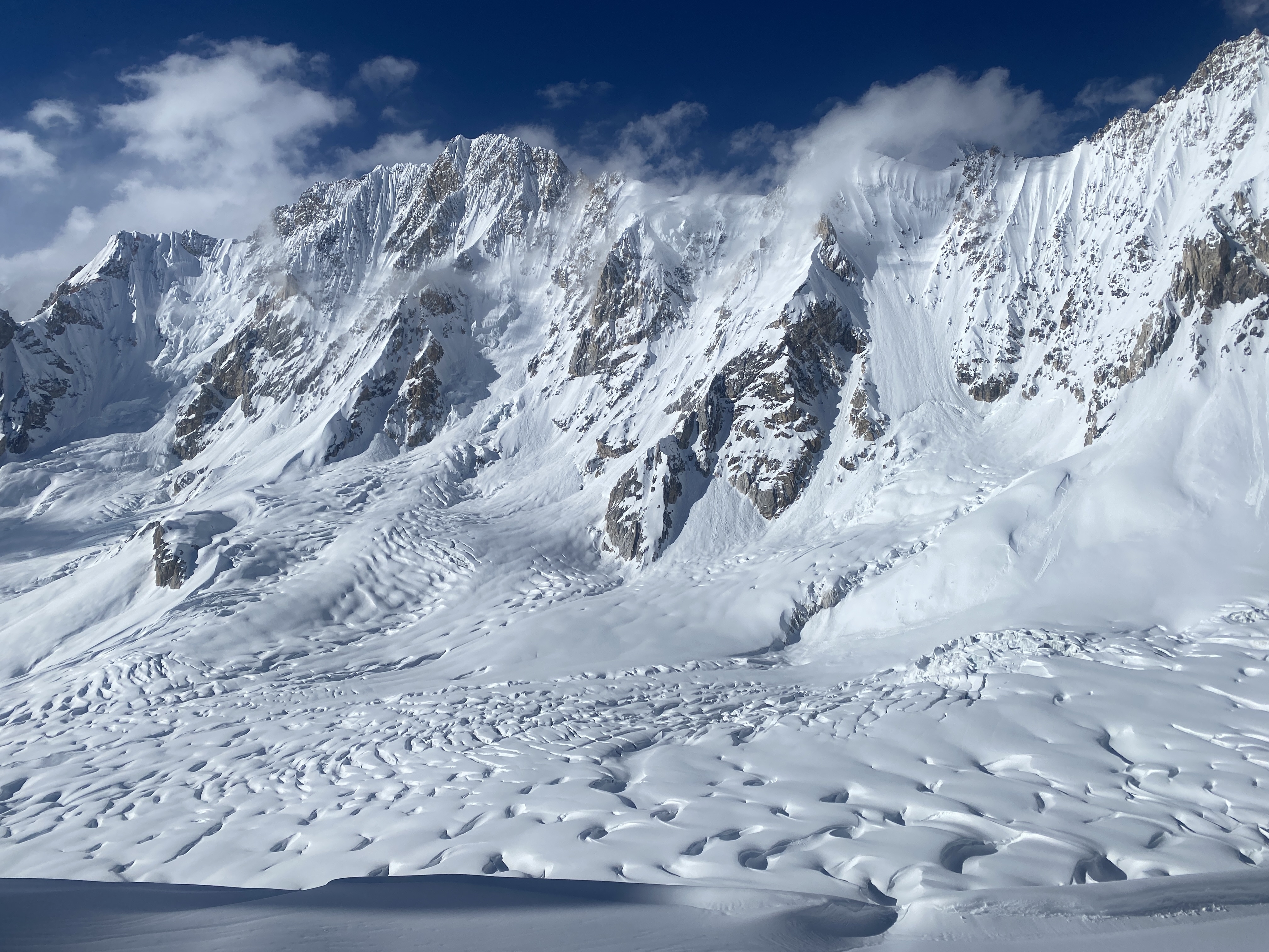 Karakoram, Pakistan - 4 October 2023 - A vast glacial moraine valley with black mountains under heavy overcast.