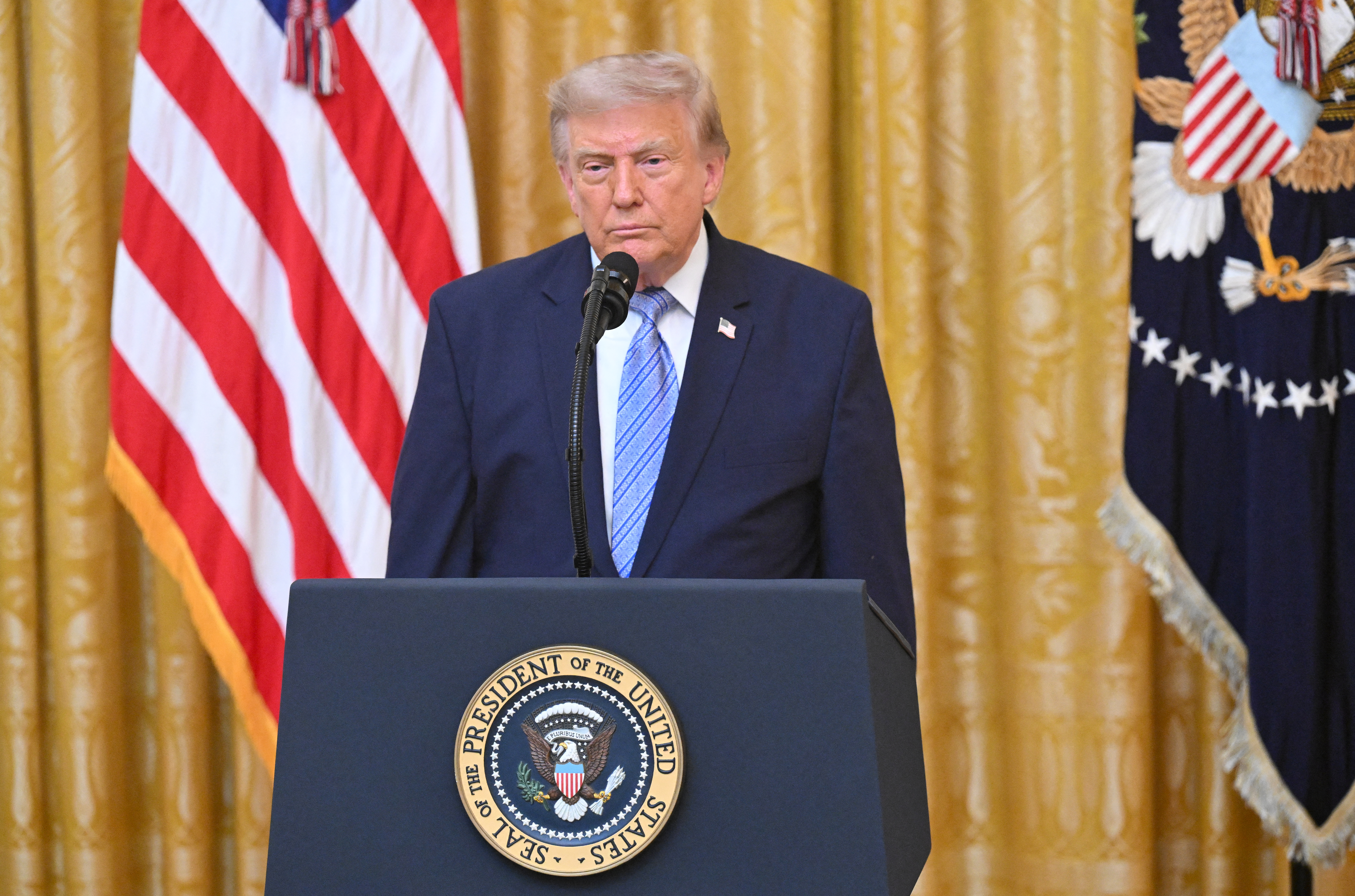 US President Donald Trump speaks at a lectern with the US flag behind him.