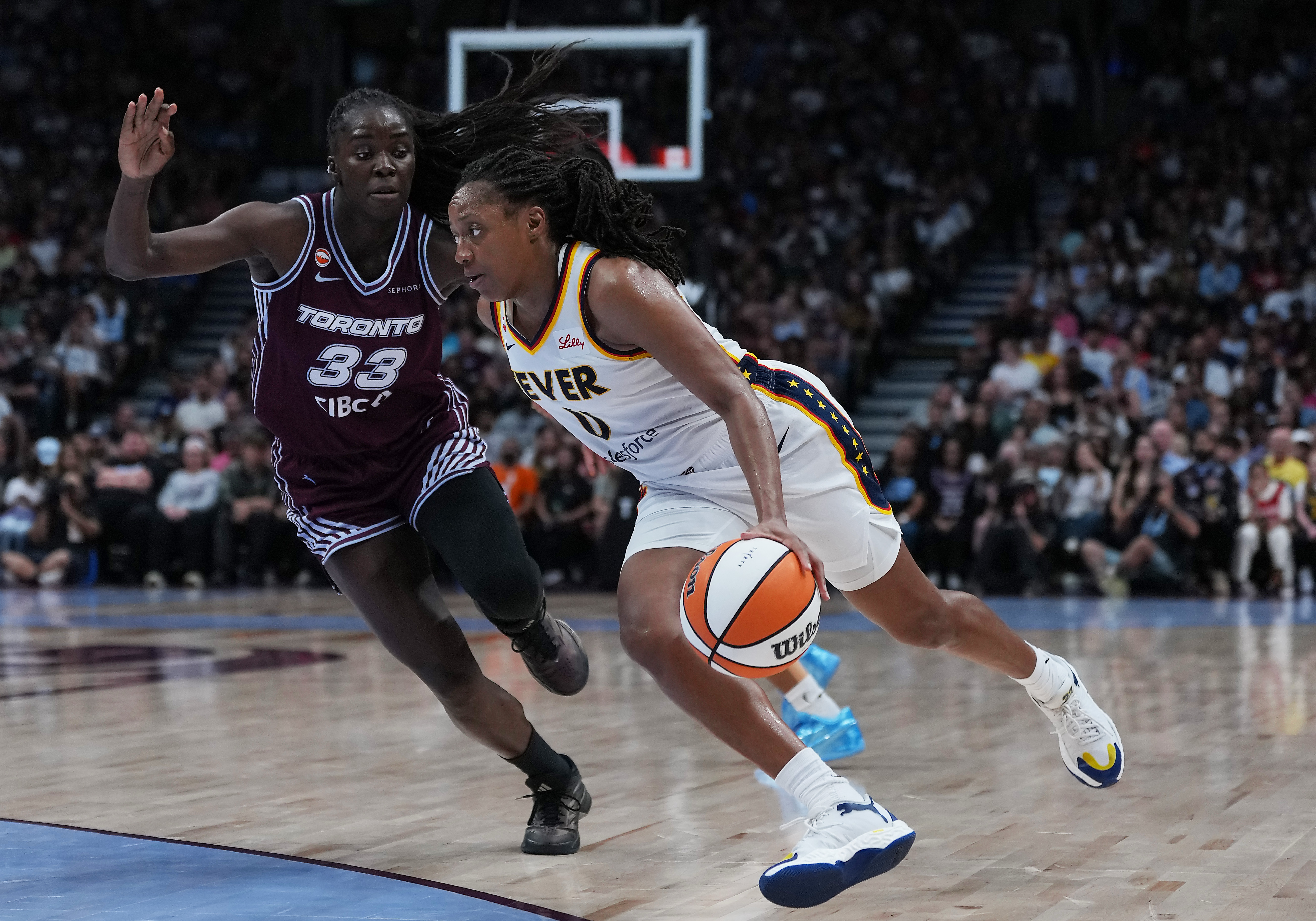 Indiana Fever guard Kelsey Mitchell (0) drives to the basket as Toronto Tempo forward Ornella Bankole (33) tries to defend.