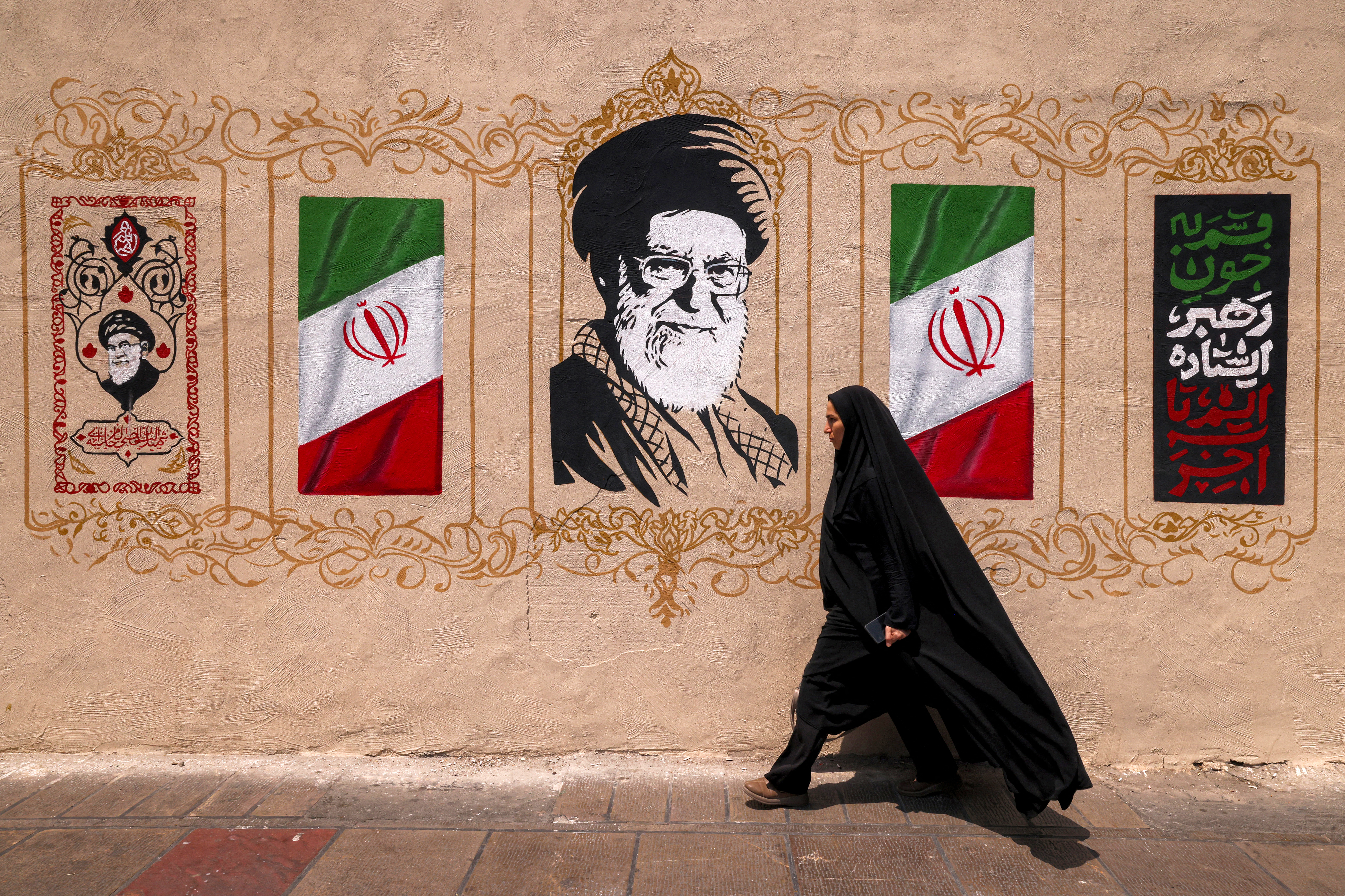 A woman walks past a mural depicting Iran's late supreme leader Ali Khamenei at Valiasr Square in central Tehran on August 8, 2026.