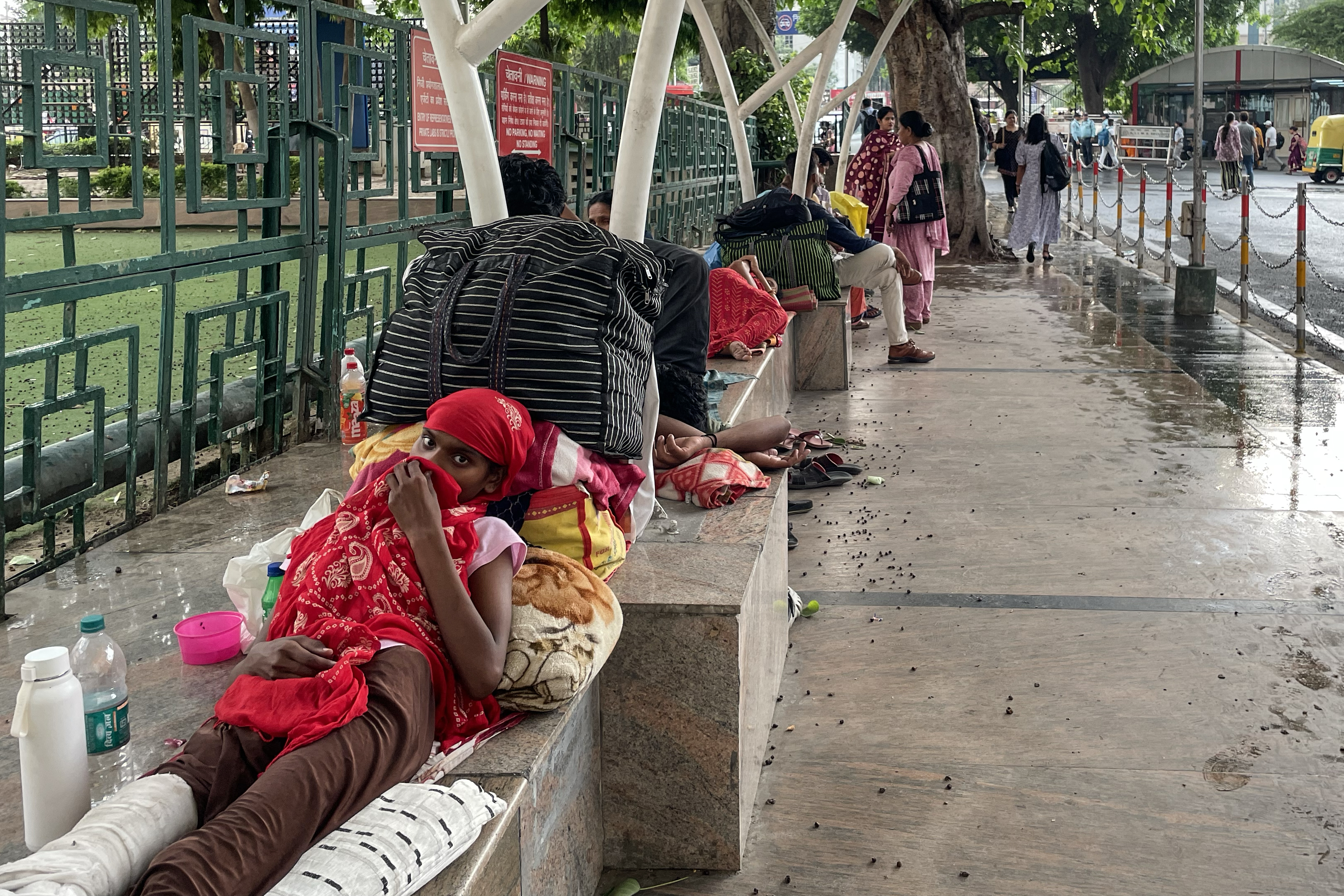 People at a bus stop next to AIIMS, New Delhi, India