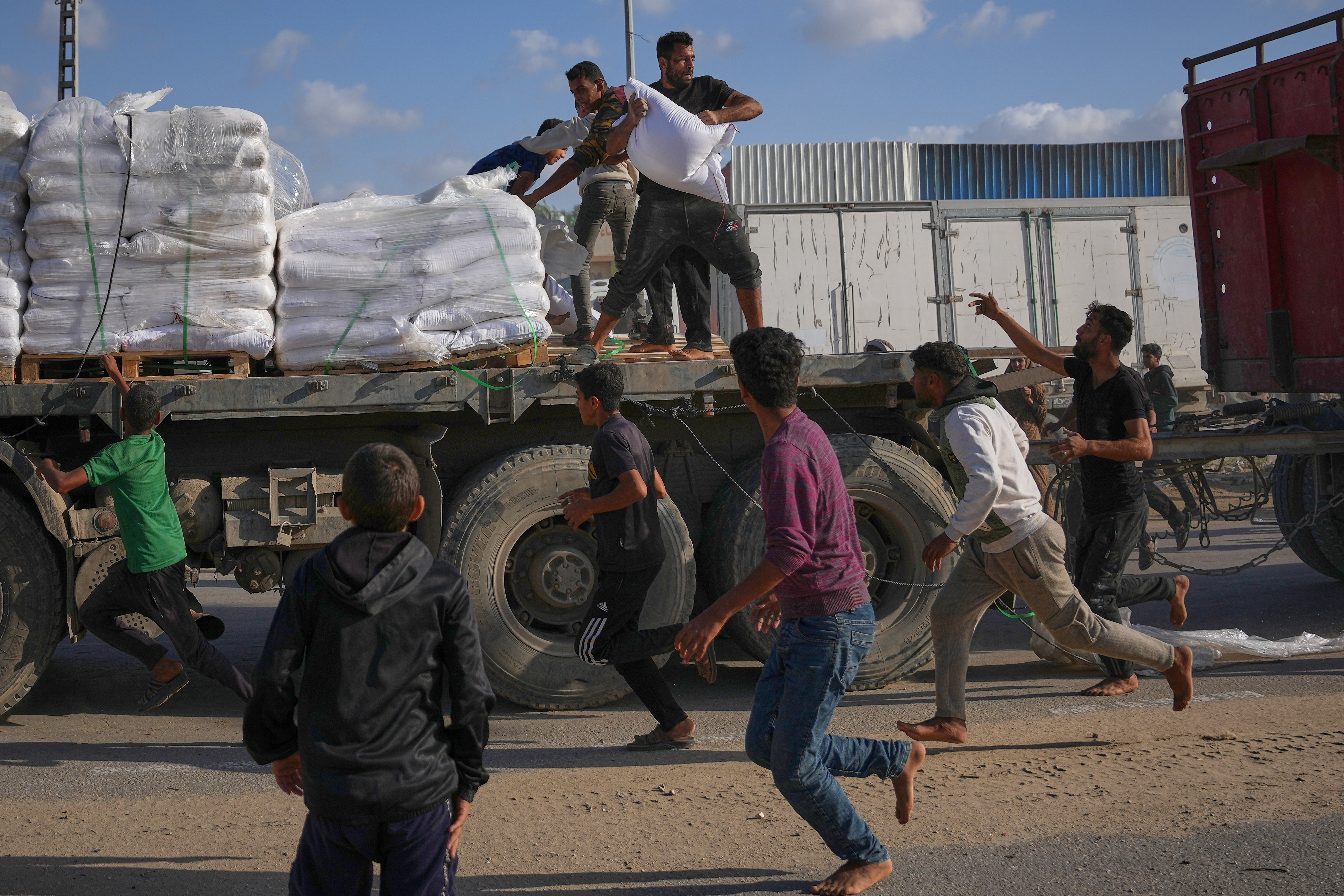 Palestinians grab sacks of flour from a moving truck carrying World Food Programme aid