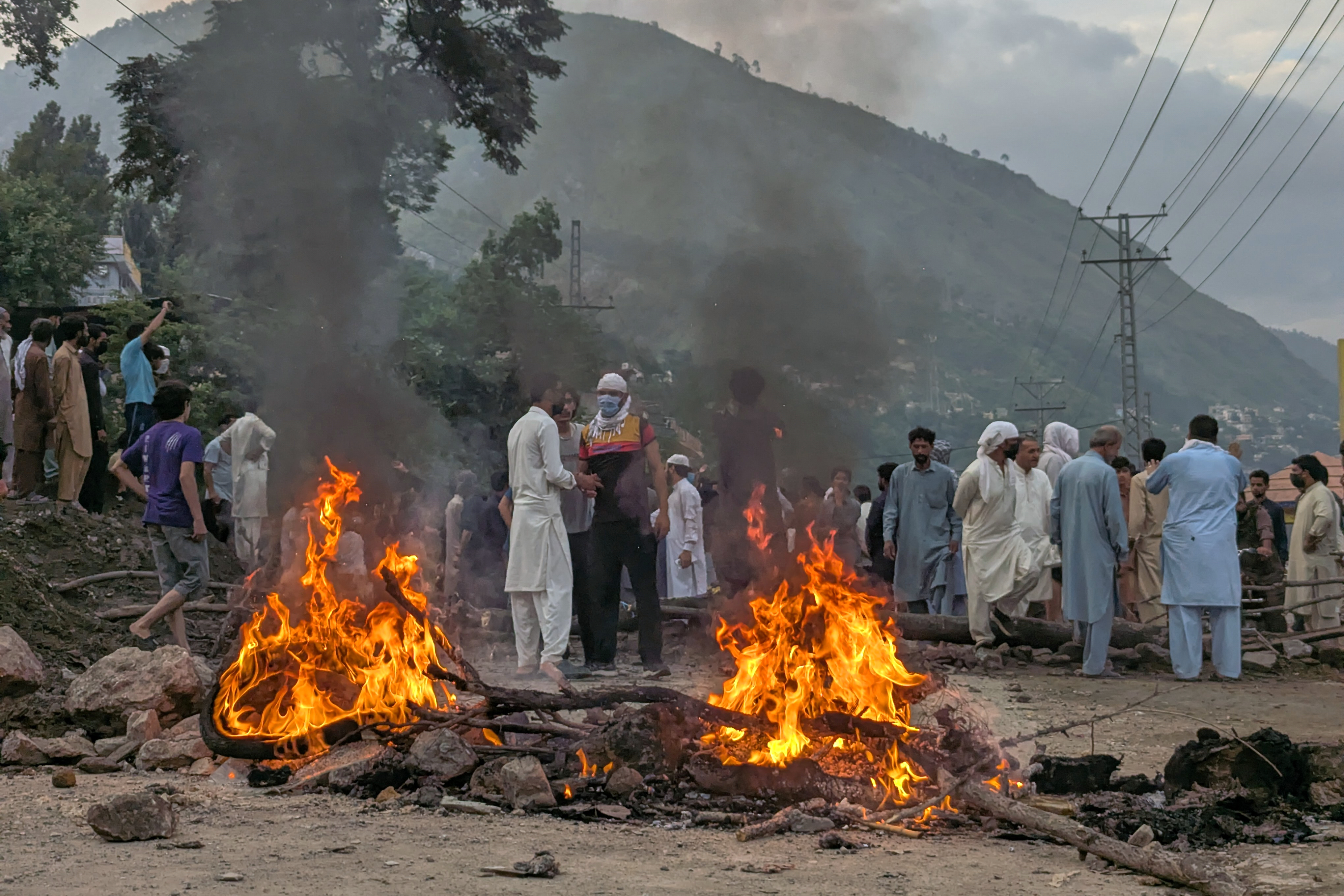 People block a road and set fire to blocks of wood amid clashes with police during a demonstration demanding greater political rights in Muzaffarabad, the capital of a region under Pakistan-administered Kashmir