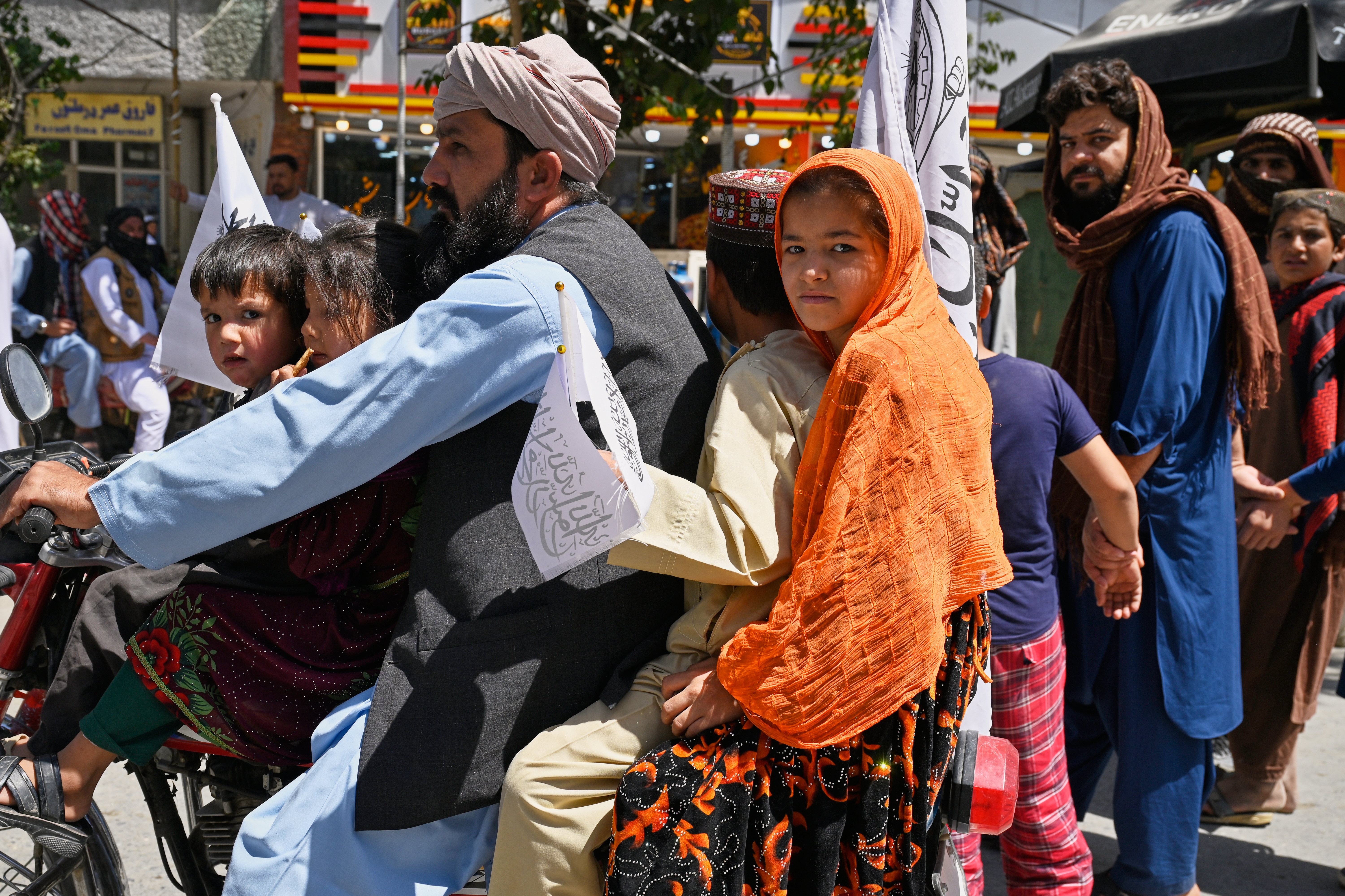 Children ride on a motorcycle carrying Taliban flags during celebrations marking the fifth anniversary of the U.S. withdrawal