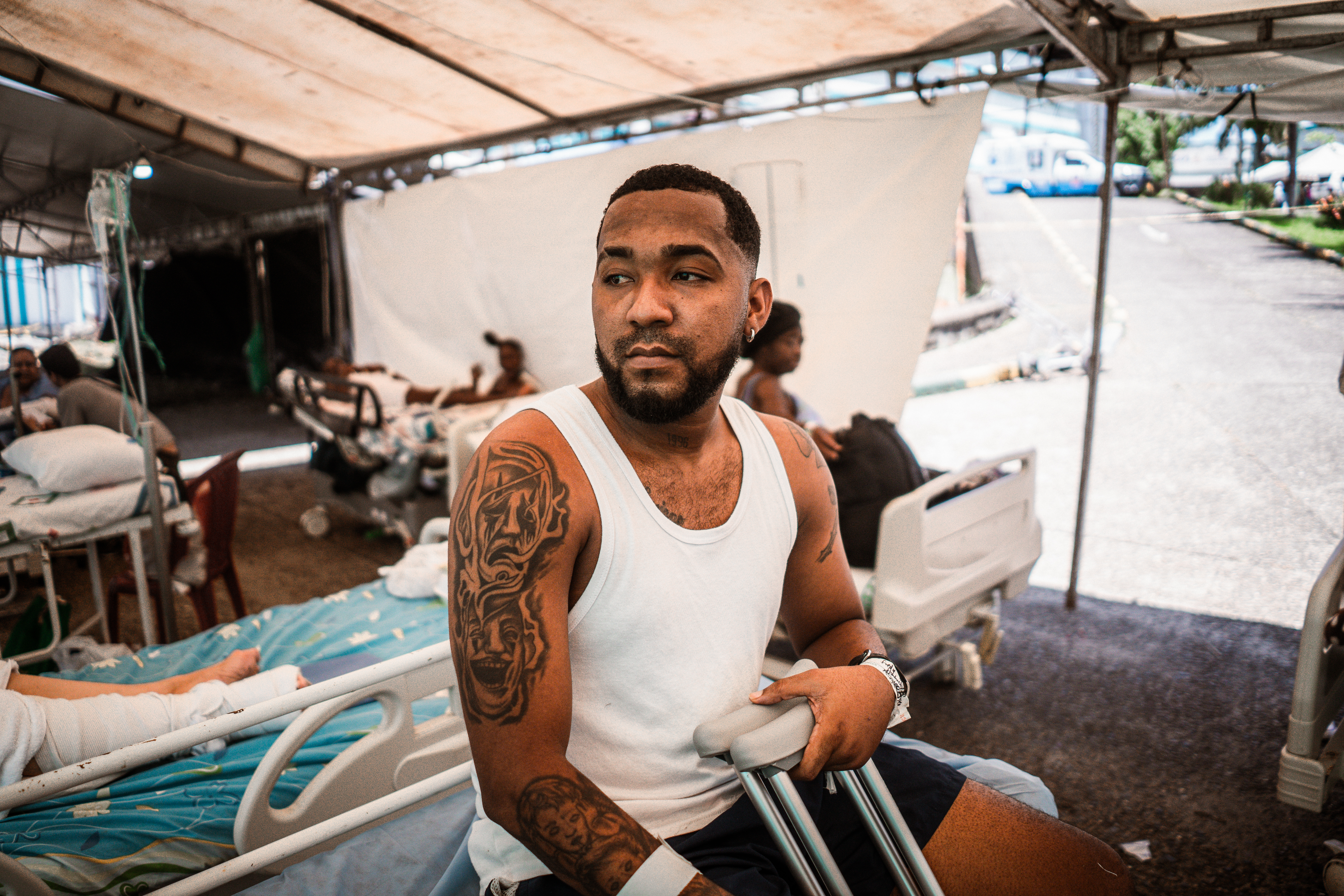 Bryan Reyes sits at the edge of his hospital bed in a temporary medical tent outside the the District Hospital Luis Ablanque De La Plata. Having sustained three fractures in his leg after jumping out of a first floor window to escape the earthquake, Reyes now feels disappointed by the state’s response to the crisis. [Euan Wallace / Al Jazeera]