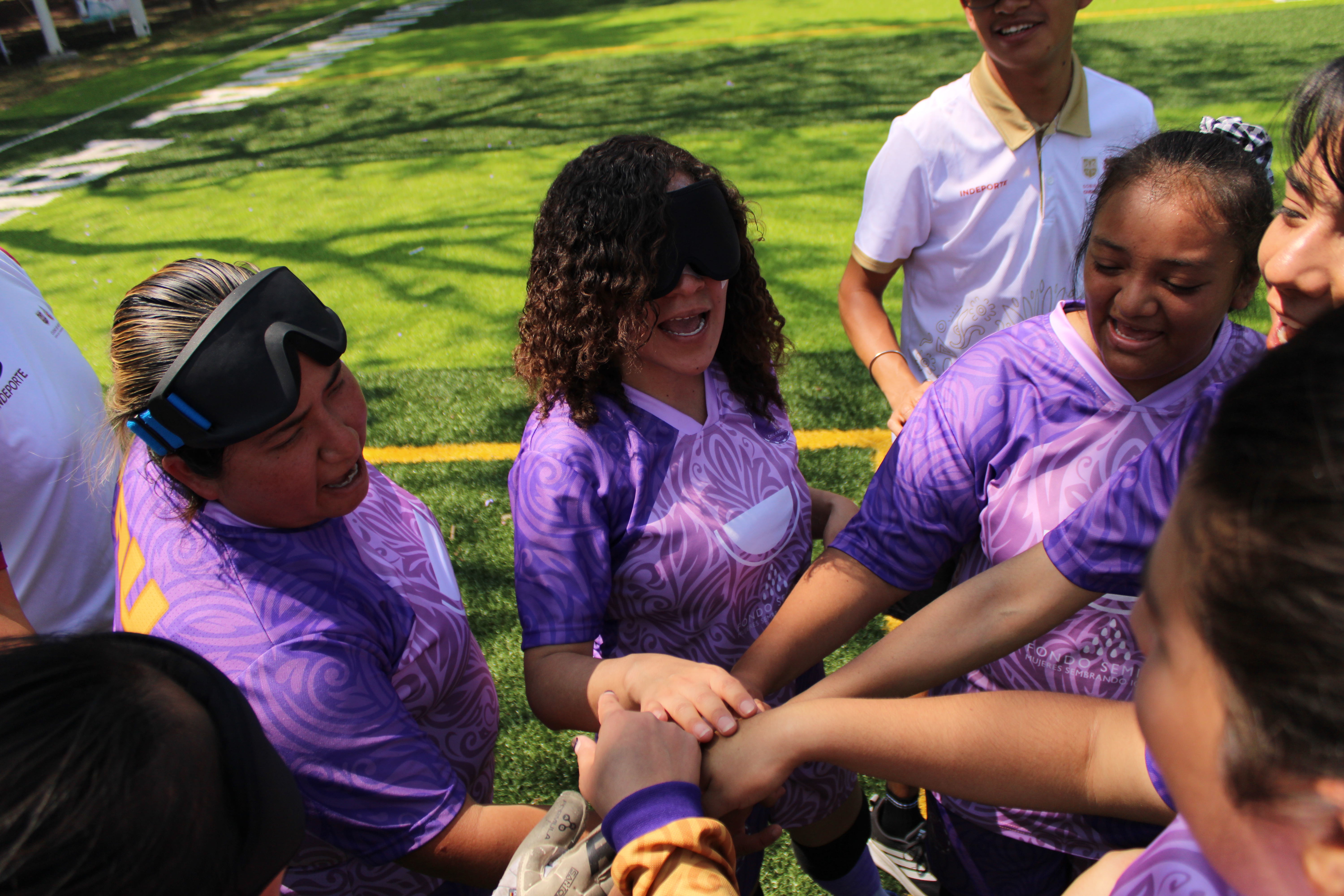 Blind women football players join hands to celebrate a win.