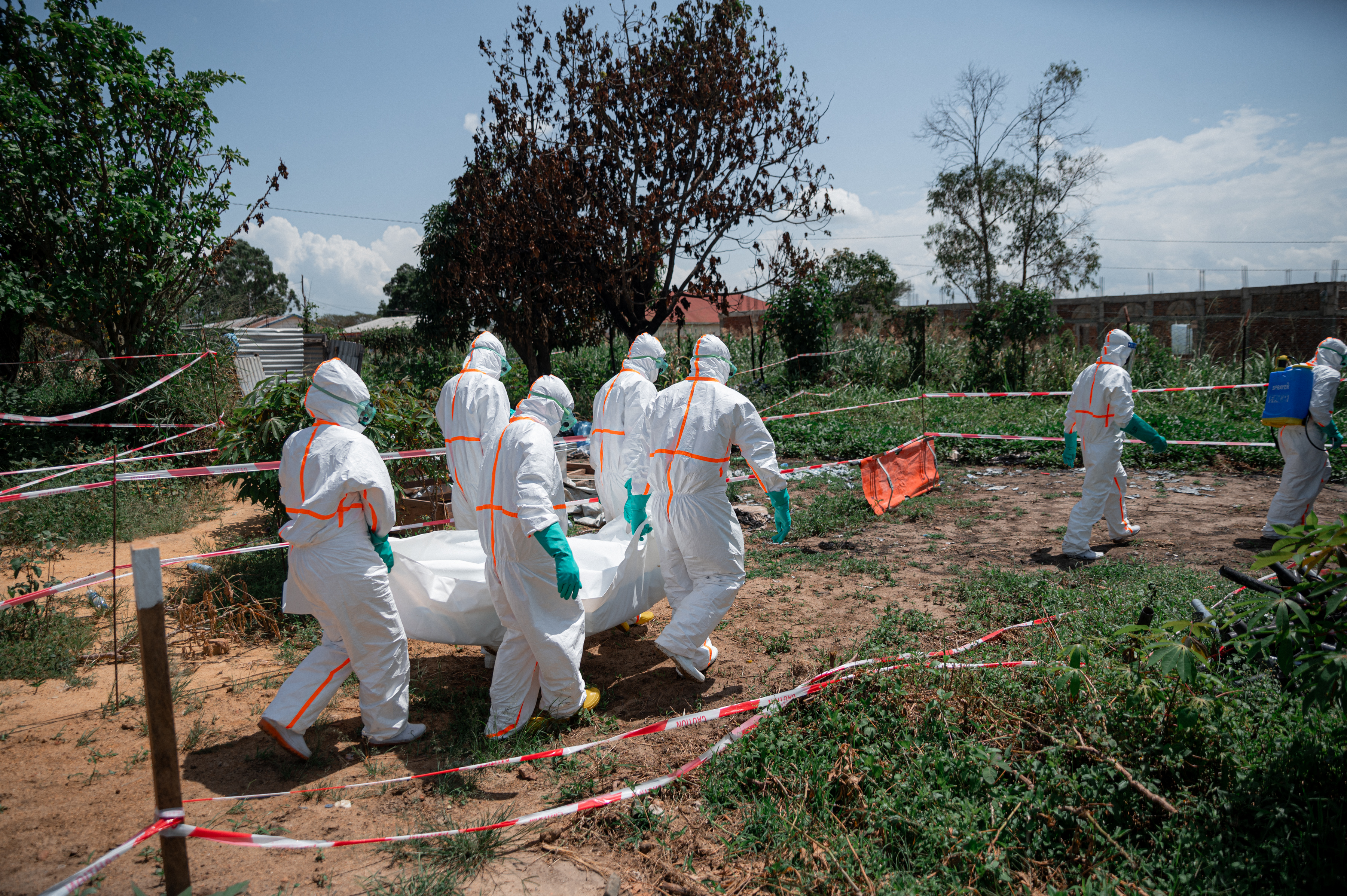 (FILES) Volunteers of the Democratic Republic of Congo Red Cross wearing personal protective equipment carry the body of an Ebola virus disease victim from the morgue of the Rwampara health centre, Ituri Province, Democratic Republic of Congo, on June 8, 2026 before loading it into a vehicle for transfer to a cemetery as part of safe and dignified burial operations aimed at preventing the spread of the virus.