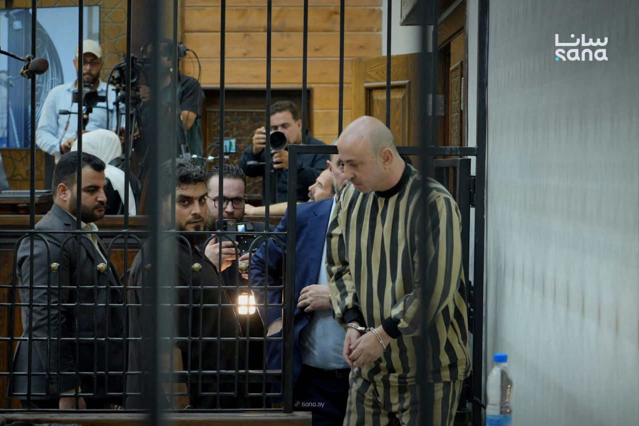This handout picture released by the official Syrian Arab News Agency (SANA) on August 18, 2026, shows Wasim al-Assad, a cousin of ousted Syrian ruler Bashar al-Assad, being led into a defendant's cage in the courtroom for his sentencing, at the Fourth Criminal Court in Damascus.