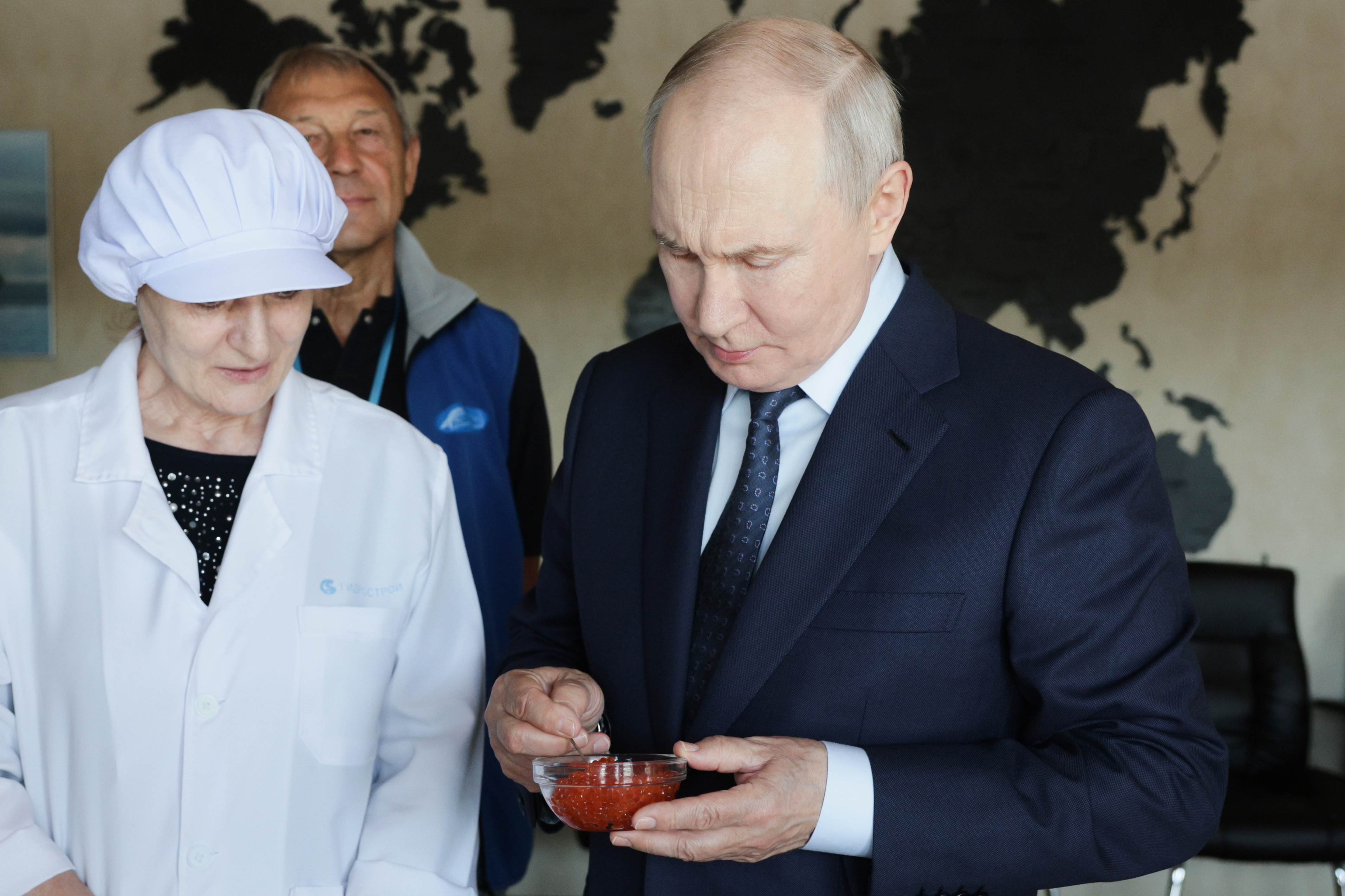 Russian President Vladimir Putin, right, tastes products as he visits a factory.