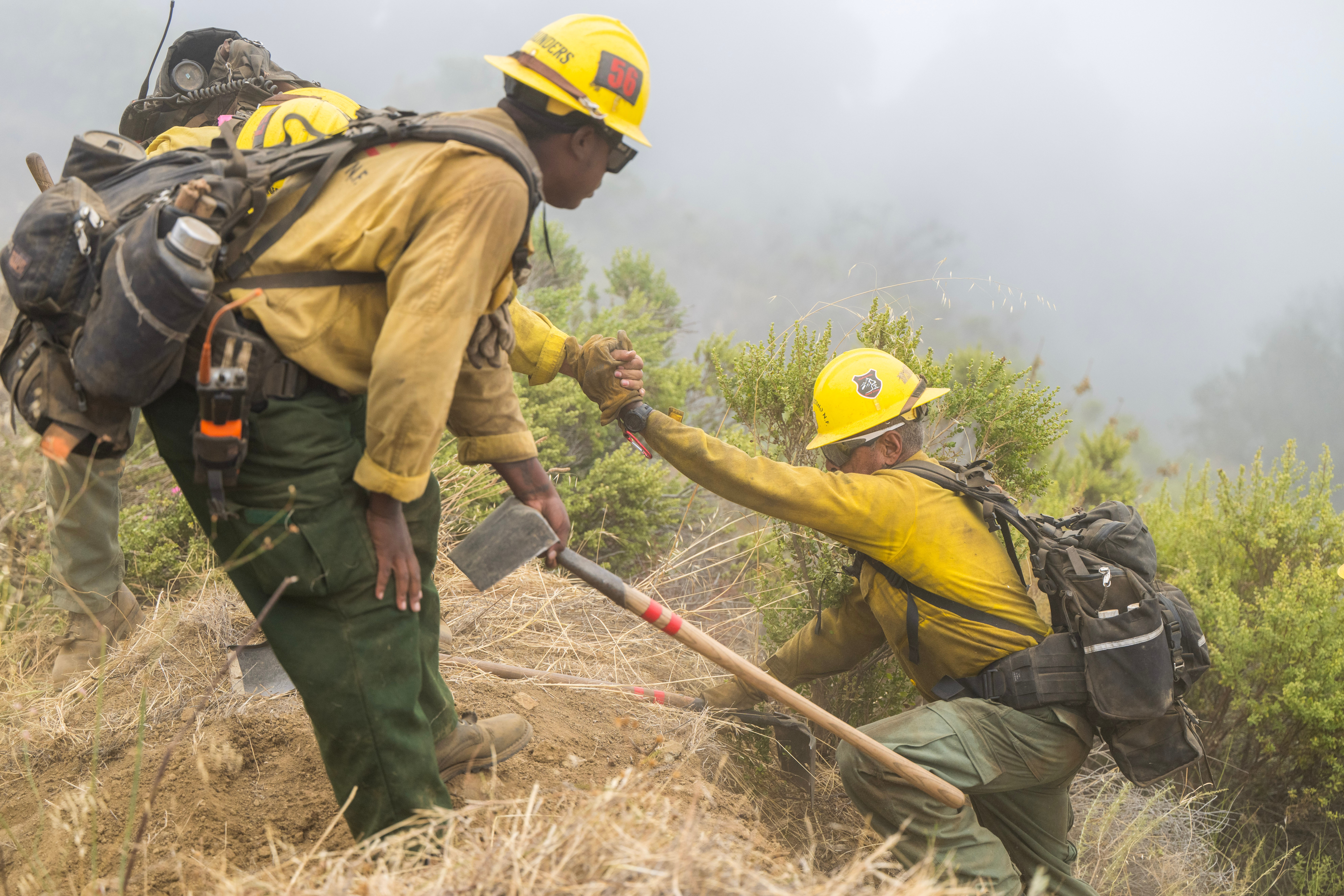 Firefighters hike out after cutting a fire break along Coast Ridge Road to help control the Timber Fire in Big Sur, Calif., Thursday, Aug. 13, 2026. (AP Photo/Nic Coury)