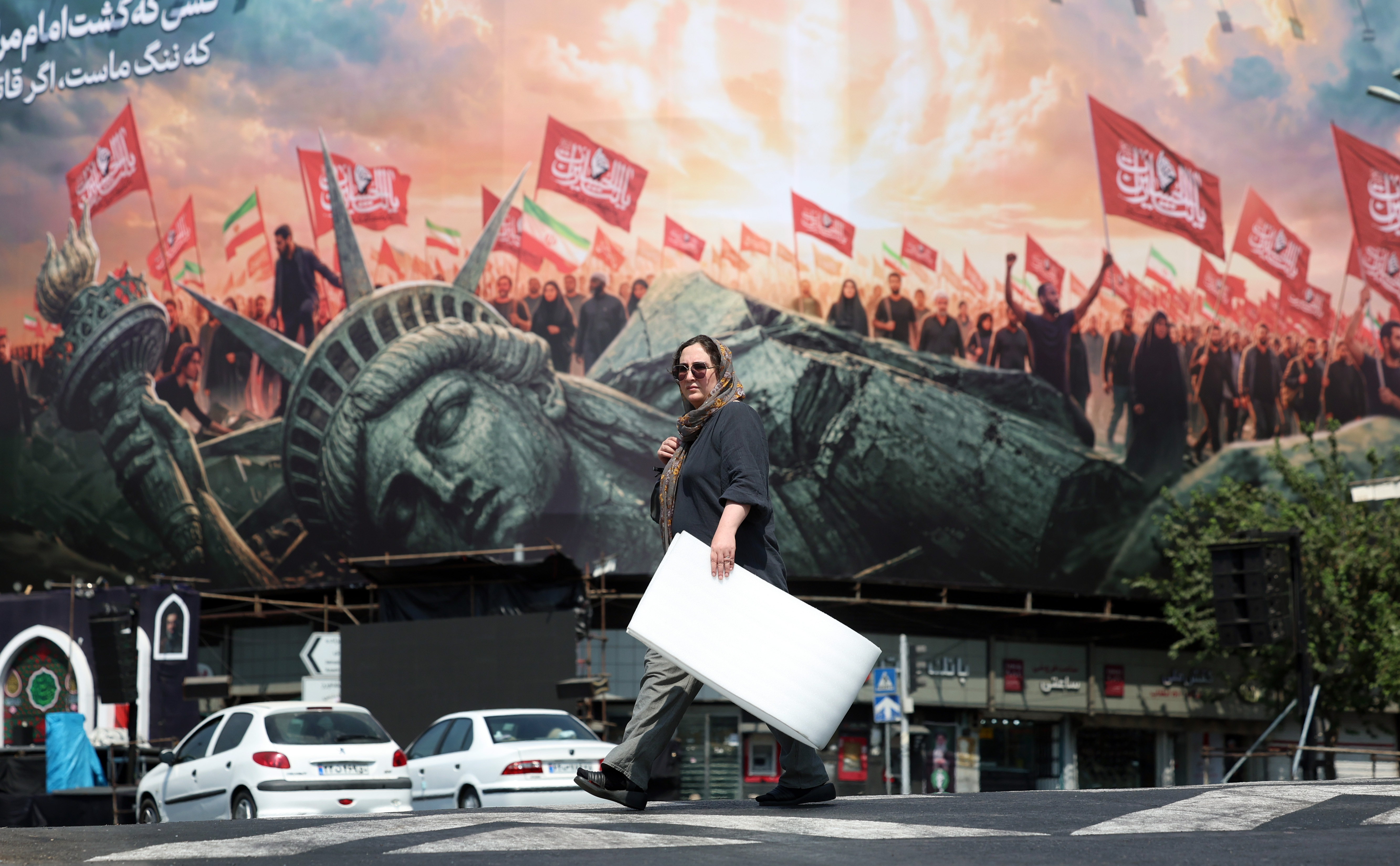 epa13165940 An Iranian woman walks next to an anti-US billboard at the Enghelab square in central Tehran, Iran, 13 August 2026. Tensions between Iran and the US remain high as opposing claims persist over shipping control in the Strait of Hormuz. EPA/ABEDIN TAHERKENAREH RESTRICTIONS: NO Access Israel Media/Persian Language TV Stations Outside Iran/Strictly No Access BBC Persian/VOA Persian/Manoto TV/Iran International TV. (As mandated by Iran's Directorate General for Foreign Media) --