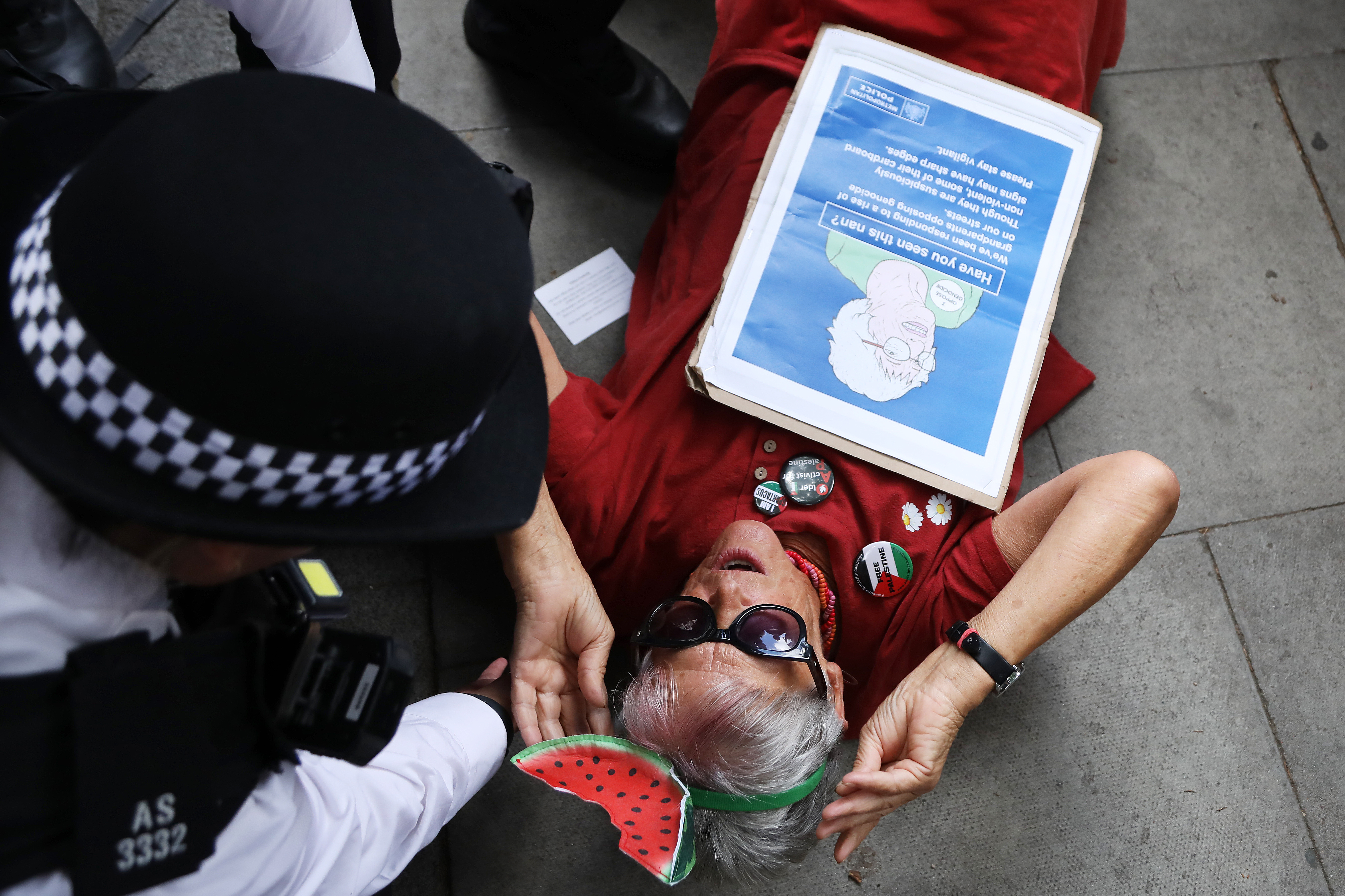LONDON, ENGLAND - JULY 30: A demonstrator lays on the pavement surrounded by police officers as the activist group Defend Our Juries hold a "Graduation Day" protest at Westminster Magistrates' Court on July 30, 2026 in London, England. The protest outside Westminster Magistrates' Court is organised by Defend Our Juries to coincide with proceedings against individuals arrested under the Terrorism Act. It involves public declarations of support for the proscribed group Palestine Action. (Photo by Alishia Abodunde/Getty Images)