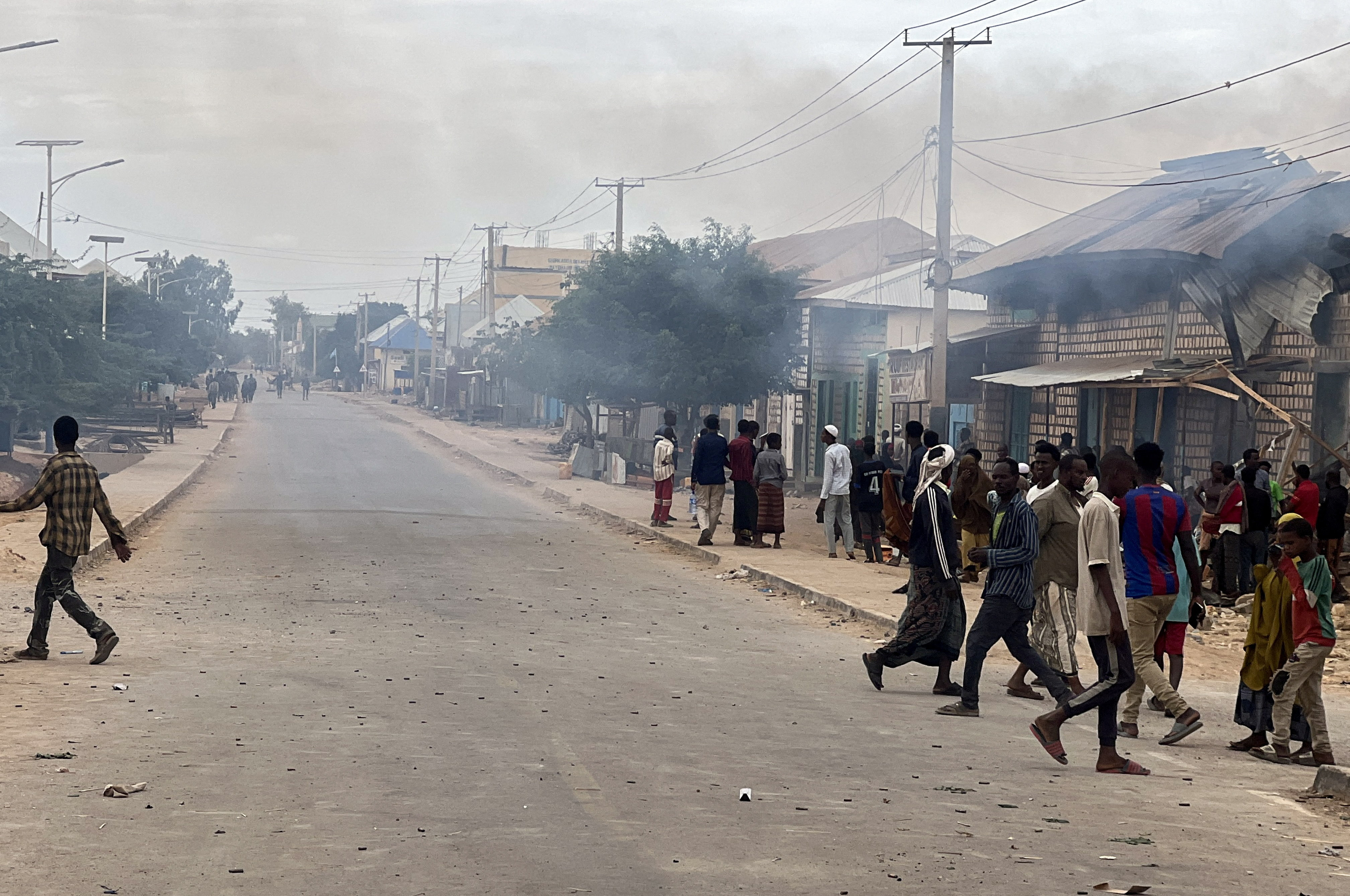 Civilians gather as smoke billows from a shop hit by artillery following clashes between Somalia's federal troops and armed opposition groups, in Baidoa, Somalia, August 17, 2026. Picture taken with a mobile phone. REUTERS/Stringer
