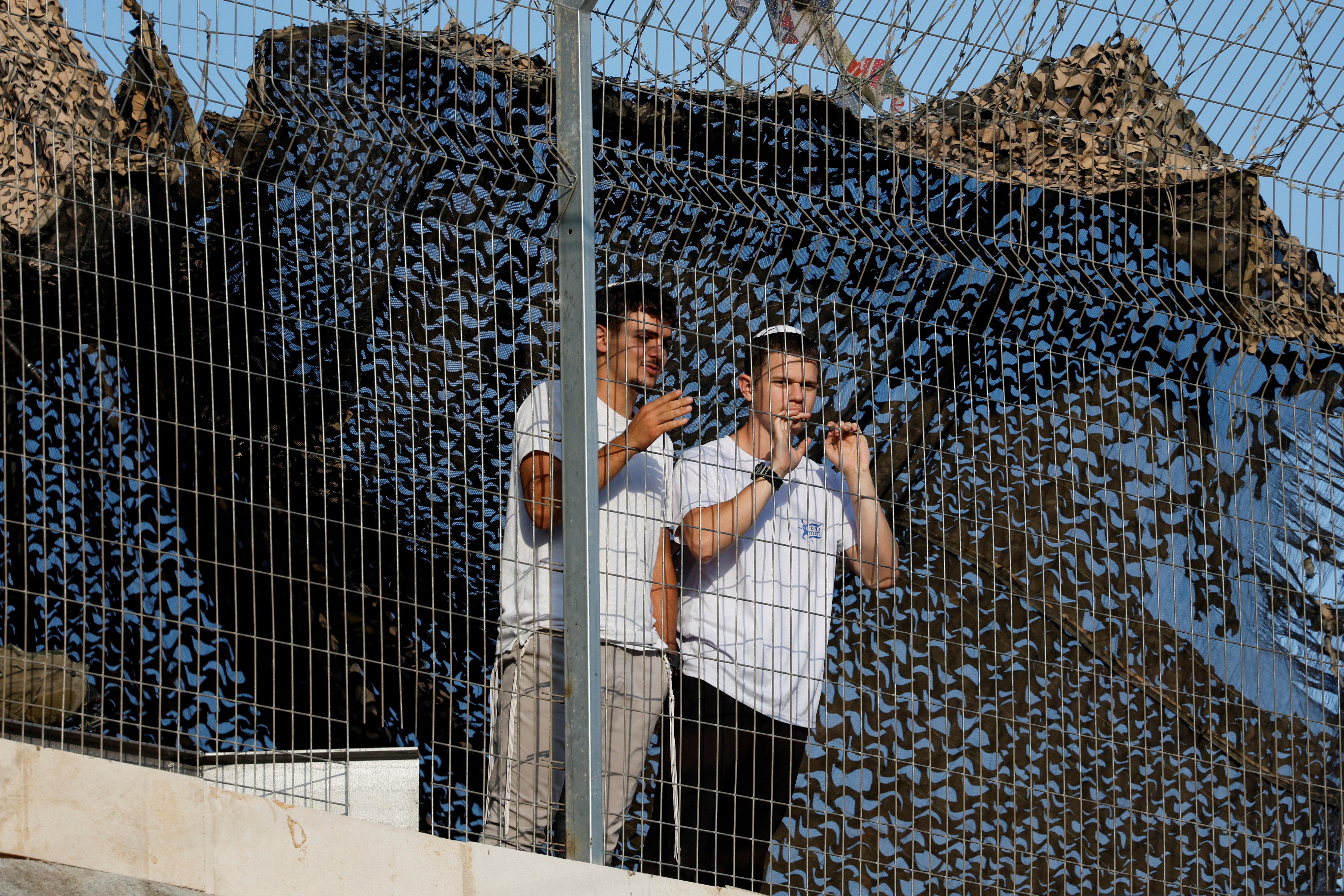 Israeli settlers look out through a metal fence during a weekly tour for settlers in Hebron, in the Israeli-occupied West Bank