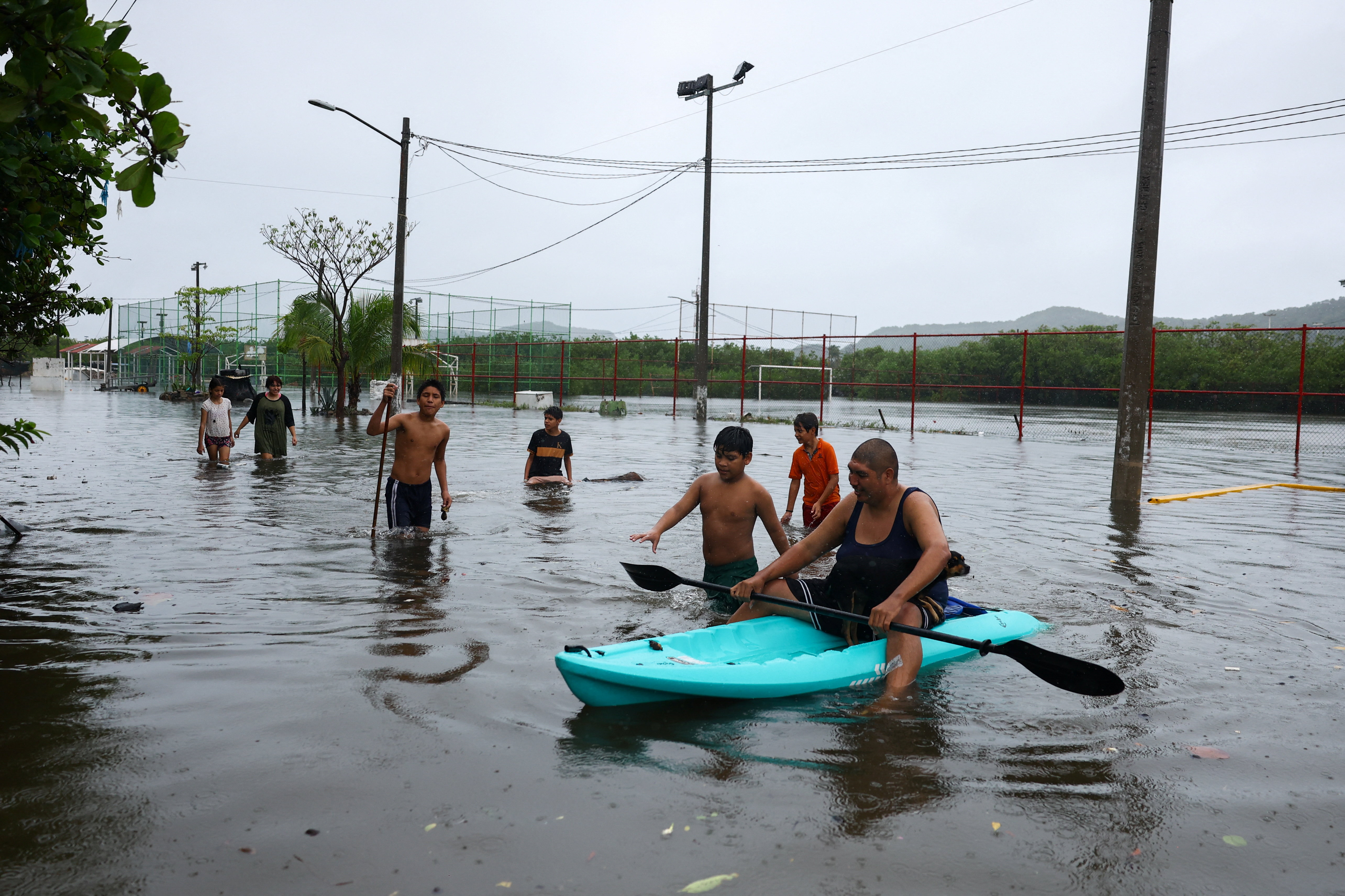 People traverse a flooded street as Hurricane Simon approaches Mexico's Pacific coast, bringing heavy rain and strong winds to Manzanillo, Mexico, October 11, 2026. REUTERS/Daniel Becerril