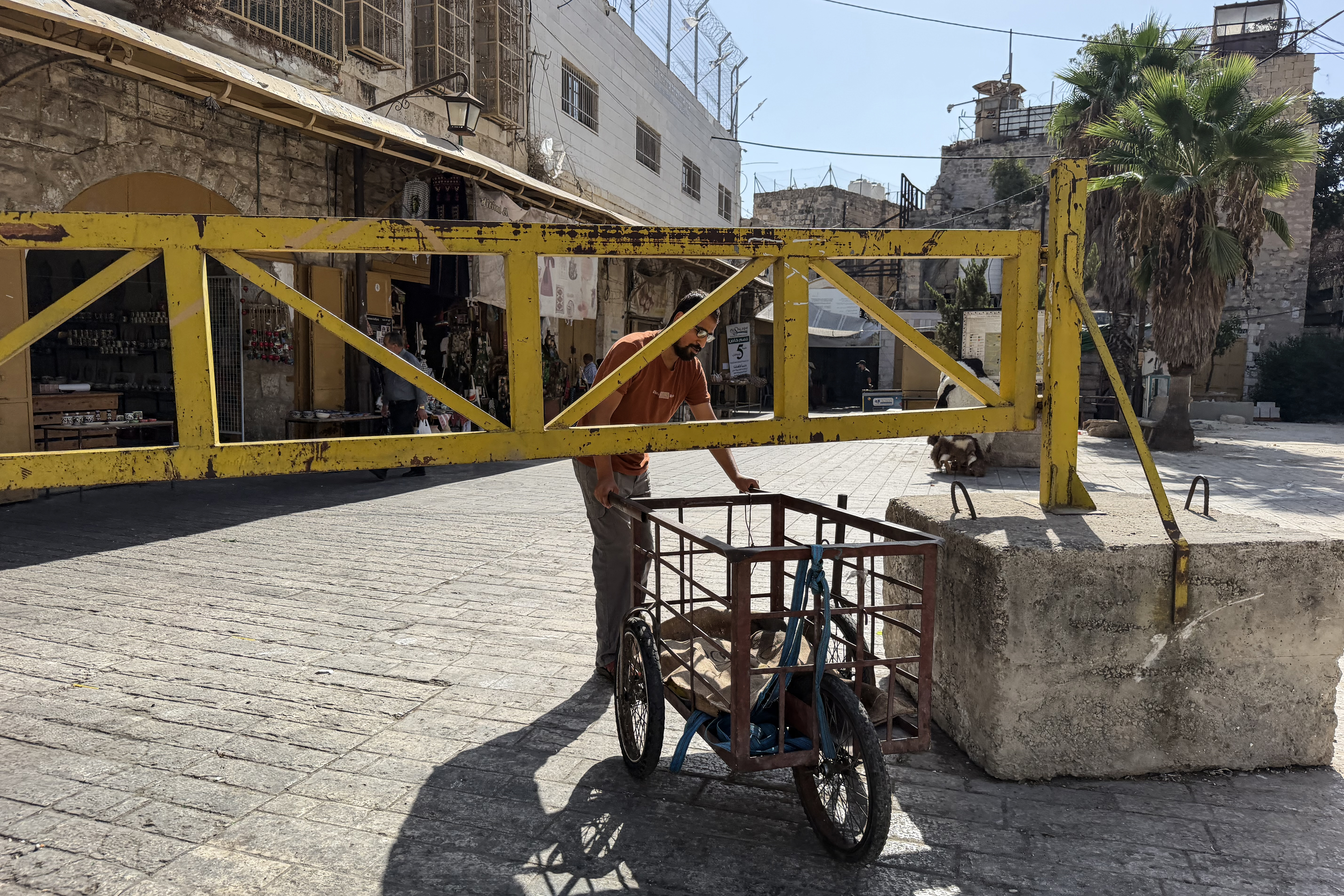A Palestinian man tries to pass under an iron gate in Hebron as Israel tightens the movement