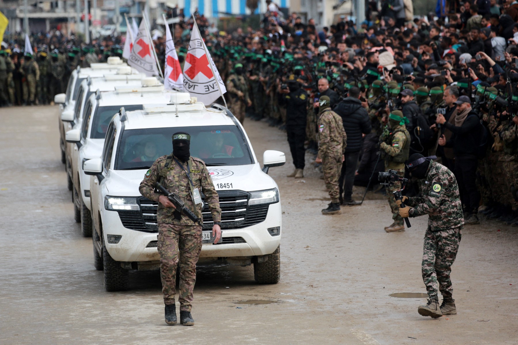 A Palestinian Hamas fighter precedes International Red Cross (ICRC) vehicles as they arrive in Nuseirat in the central Gaza Strip to receive three Israeli hostages as part of the seventh hostage-prisoner swap on February 22, 2025. Three more Israeli hostages were freed by Hamas militants at a ceremony in central Gaza on February 22 after two others were released in the southern part of the Palestinian territory. (Photo by Bashar TALEB / AFP)