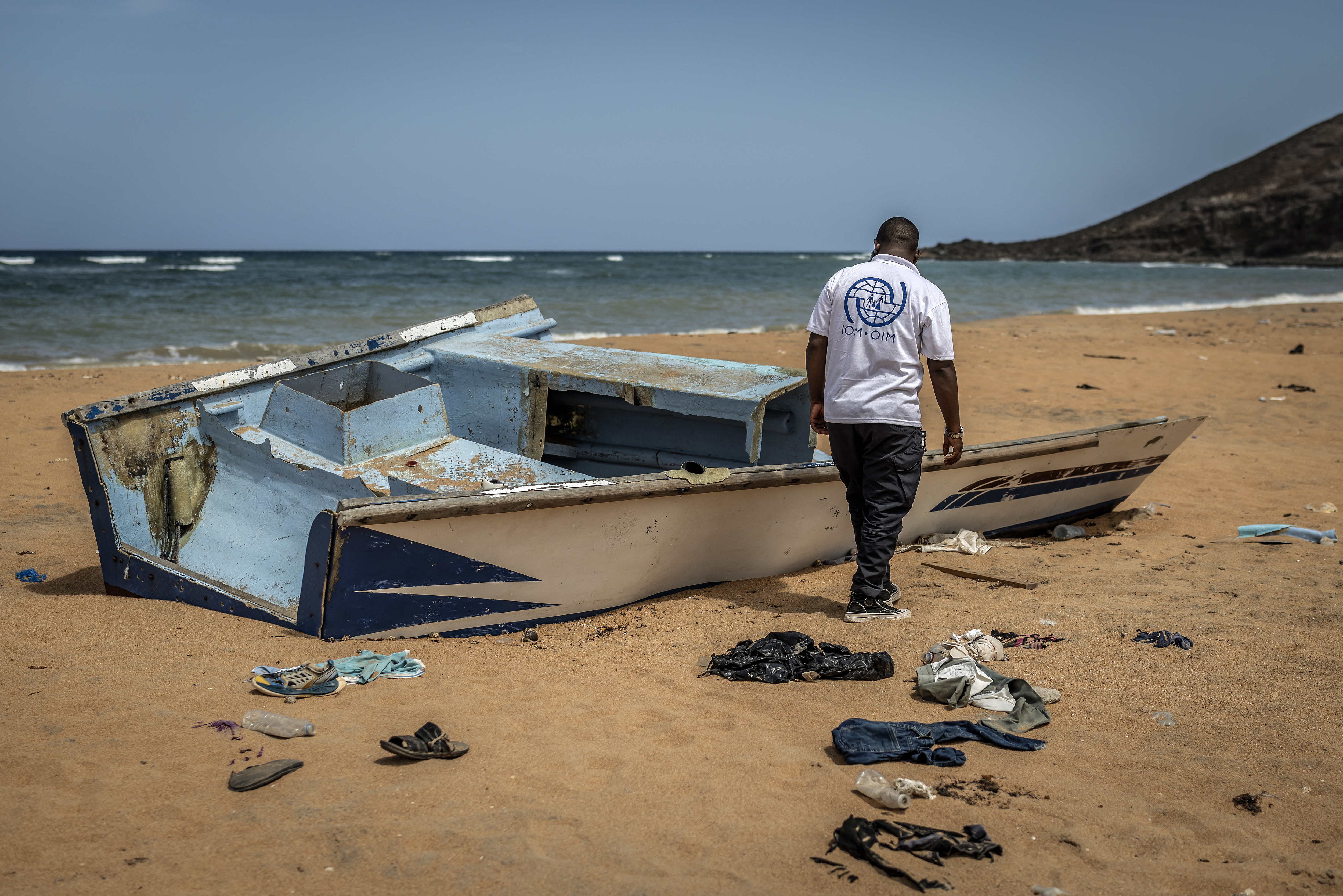 A member of the International Organization for Migration (IOM) inspects the abandoned wreckage of a boat that capsized while attempting to transport migrants to Yemen along the so-called Eastern Route at Gehere beach, near Obock