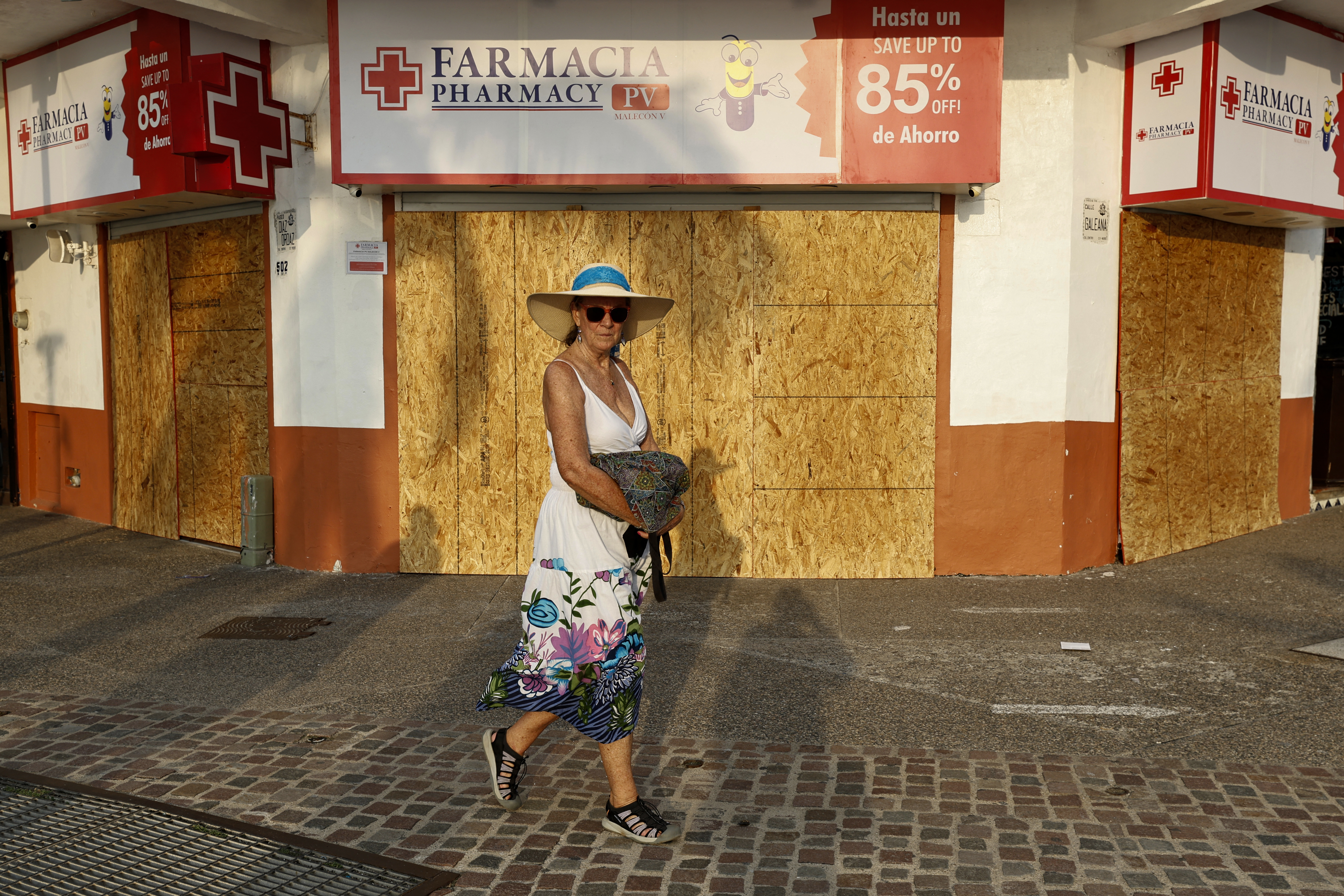 A tourist walks past a business boarded up for protection in an area threatened by the potential impact of Hurricane Simon in Puerto Vallarta, Jalisco state, Mexico, on October 9, 2026. Hurricane Simon is forecast to rapidly strengthen before striking Mexico's Pacific coast, the US National Hurricane Center said on october 9. (Photo by ULISES RUIZ / AFP)