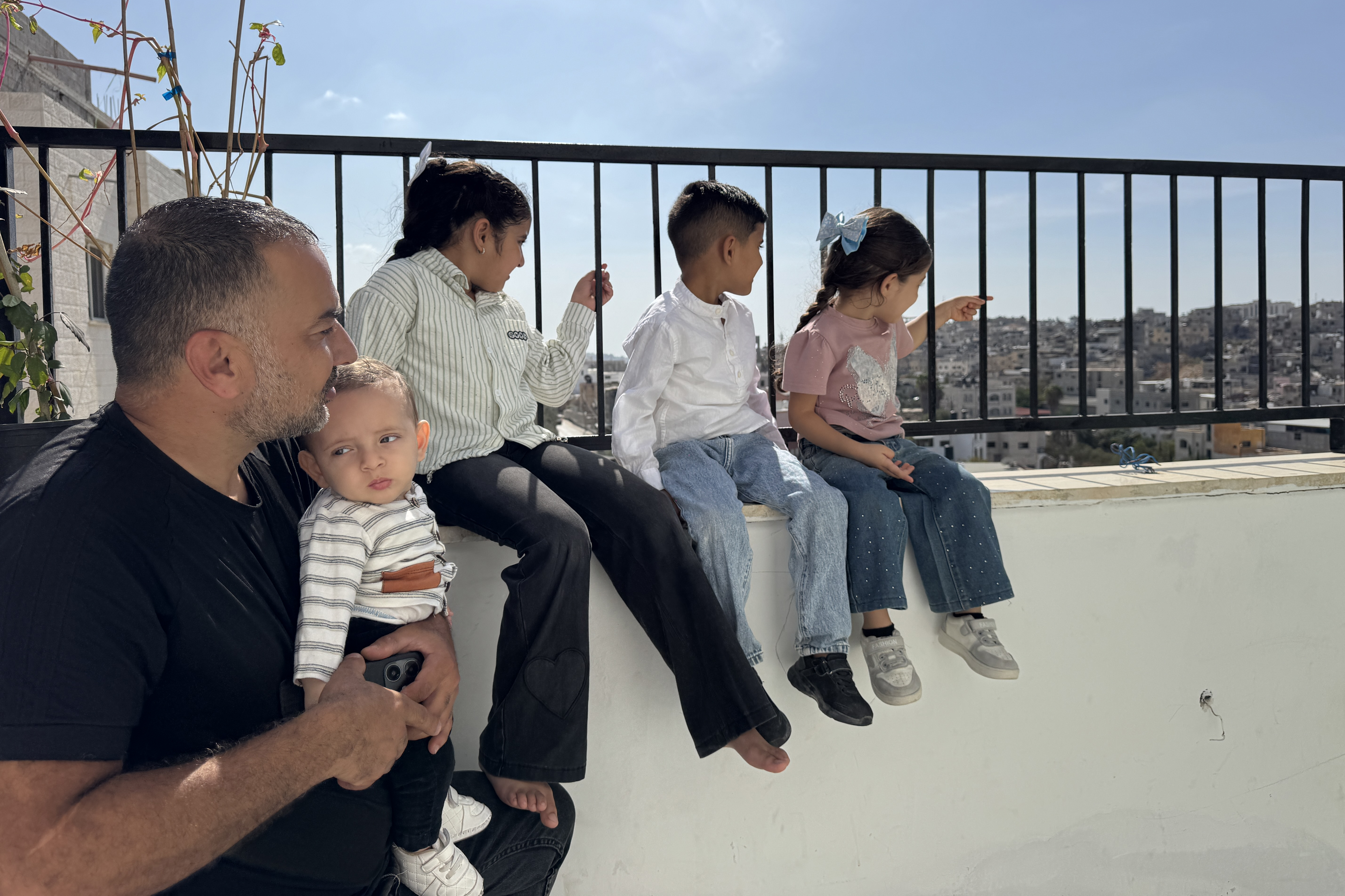 Fuad Abu Salam sits with his children in his rented apartment overlooking the Tulkarm camp gazing at their destroyed home Photo by Raghad Salameh-1791892542
