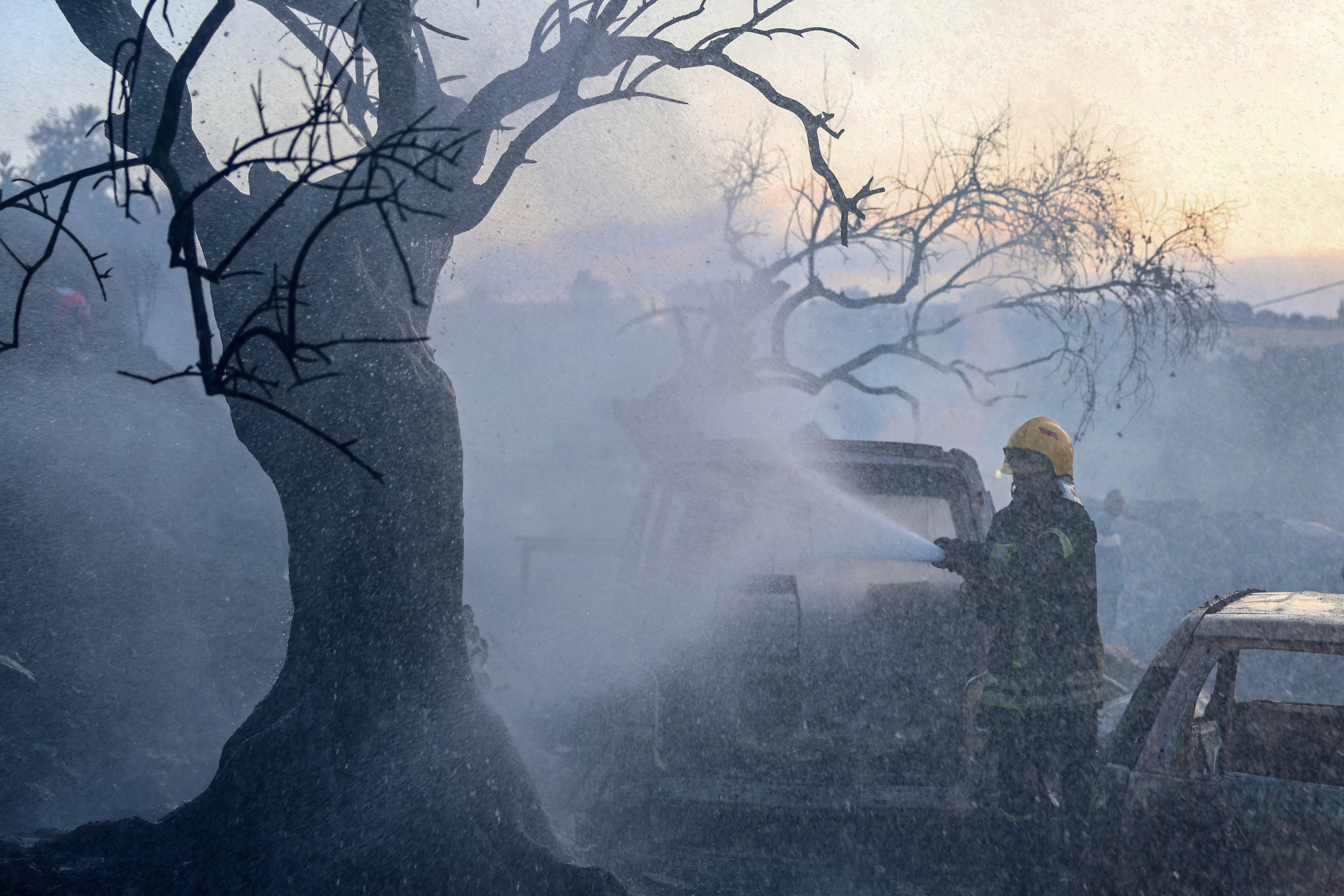 A Palestinian civil defence firefighter extinguishes a fire that burnt through cars and olive trees at a scrapyard following an attack allegedly carried out by Israeli settlers in the village of Ayn Yabrud, northeast of Ramallah, in the Israeli-occupied West Bank, on October 4, 2026.