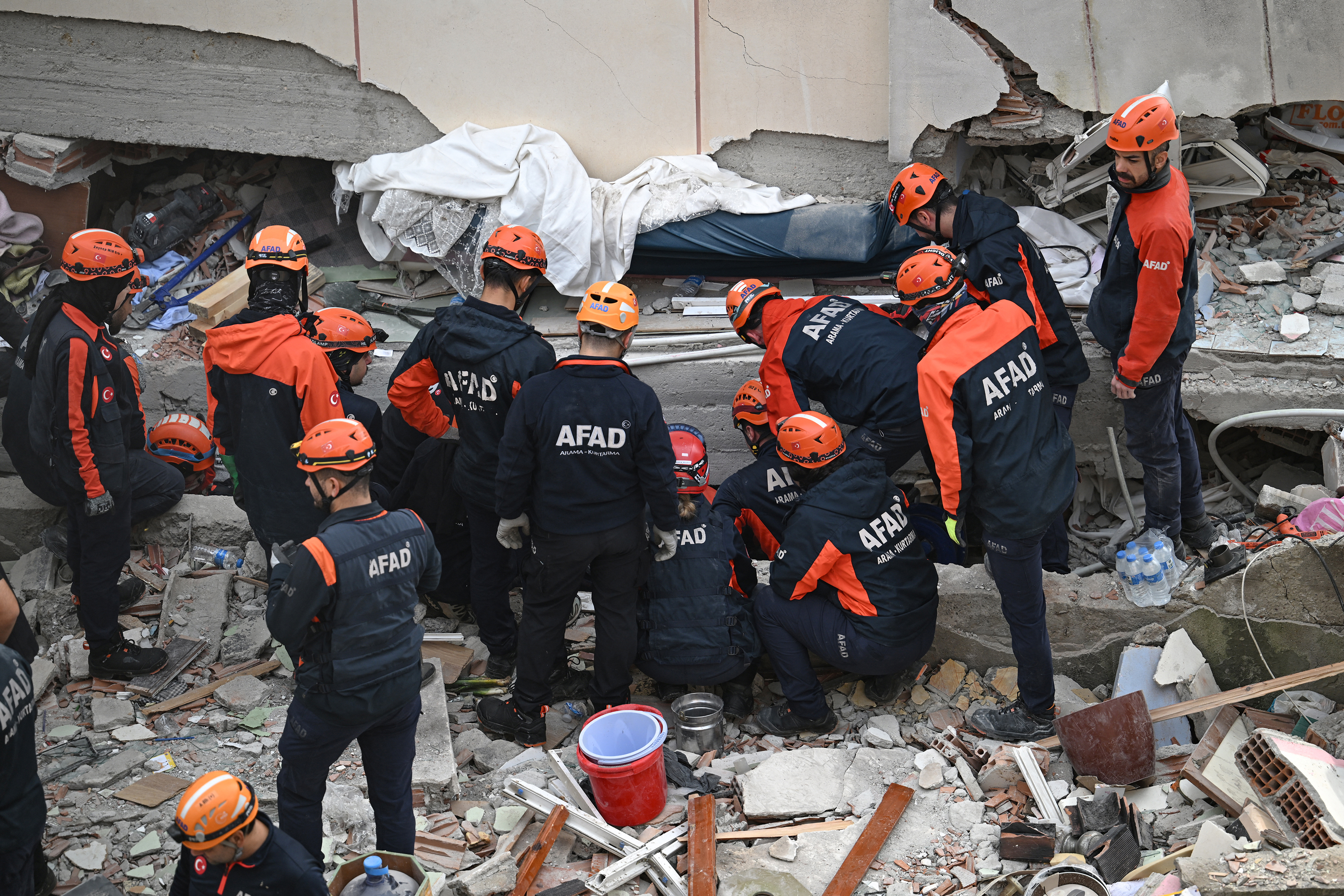 Firefighters and rescuers work among the rubble of a collapsed building.