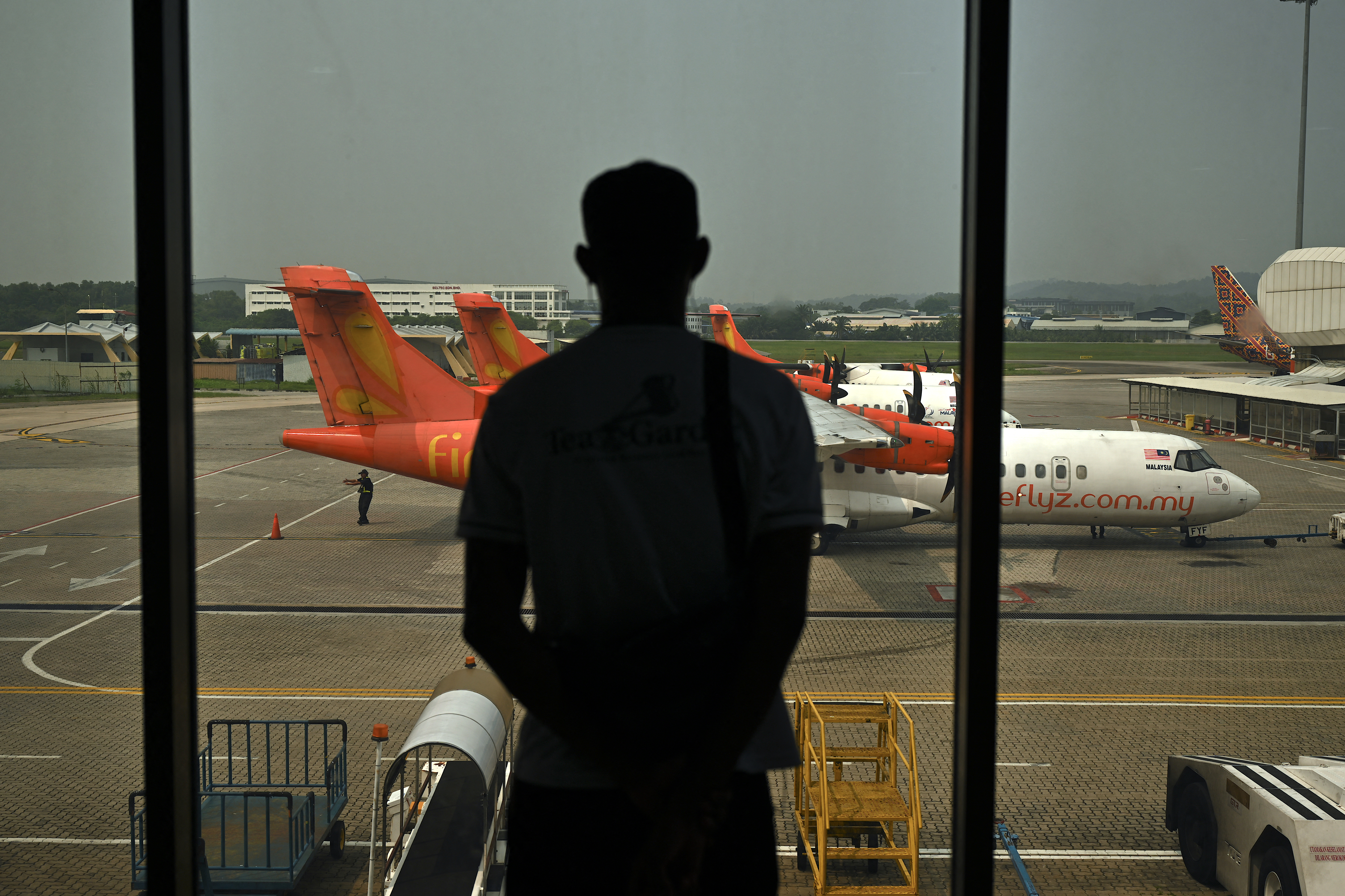 A passenger looks at Firefly aircraft parked on the tarmac at an airport.