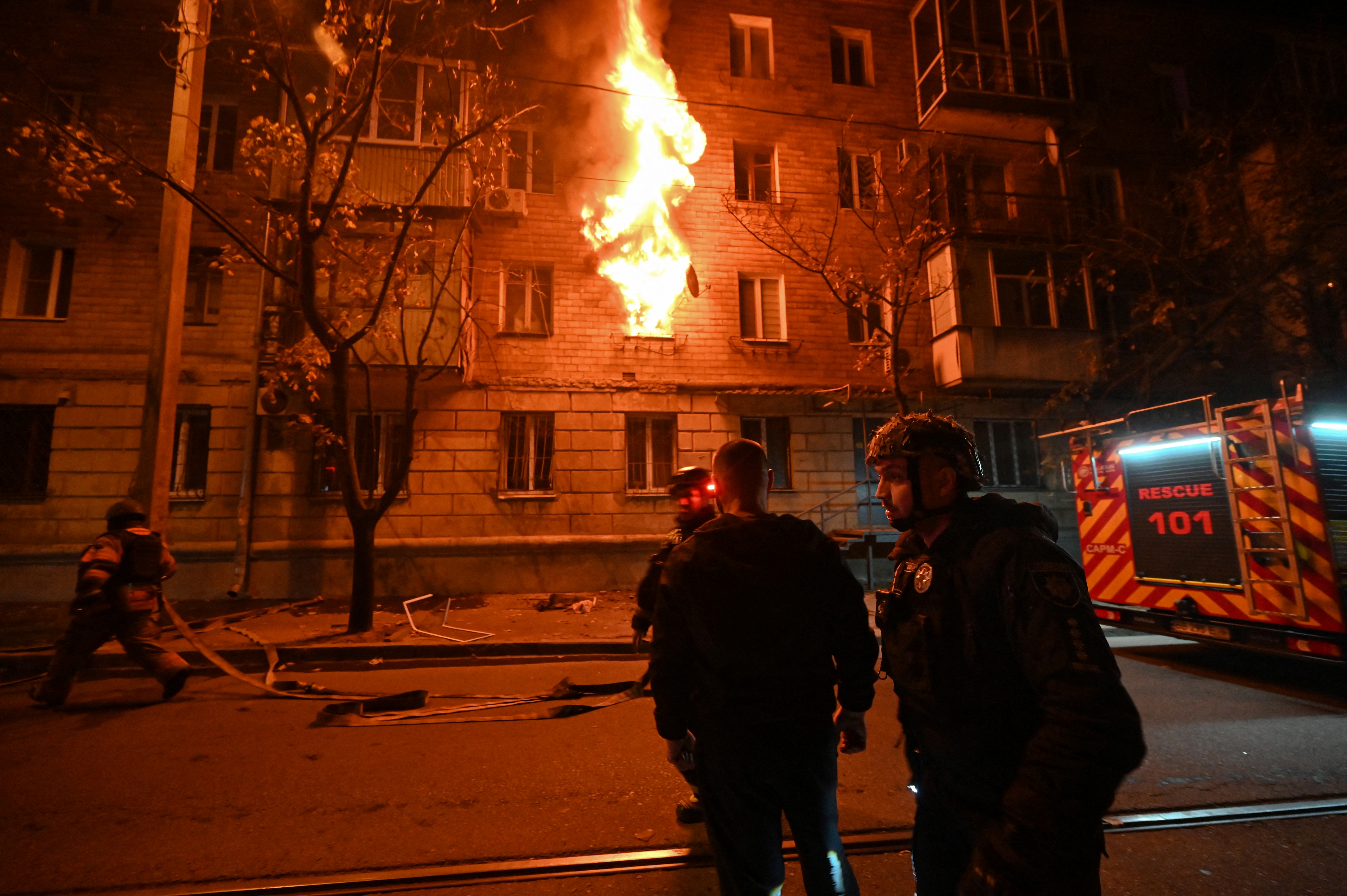 Ukrainian policemen and firefighters work at the site of a Russian drone strike at a multi-floor residential building in Kharkiv, late on October 12, 2026, amid the Russian invasion of Ukraine. (Photo by SERGEY BOBOK / AFP)