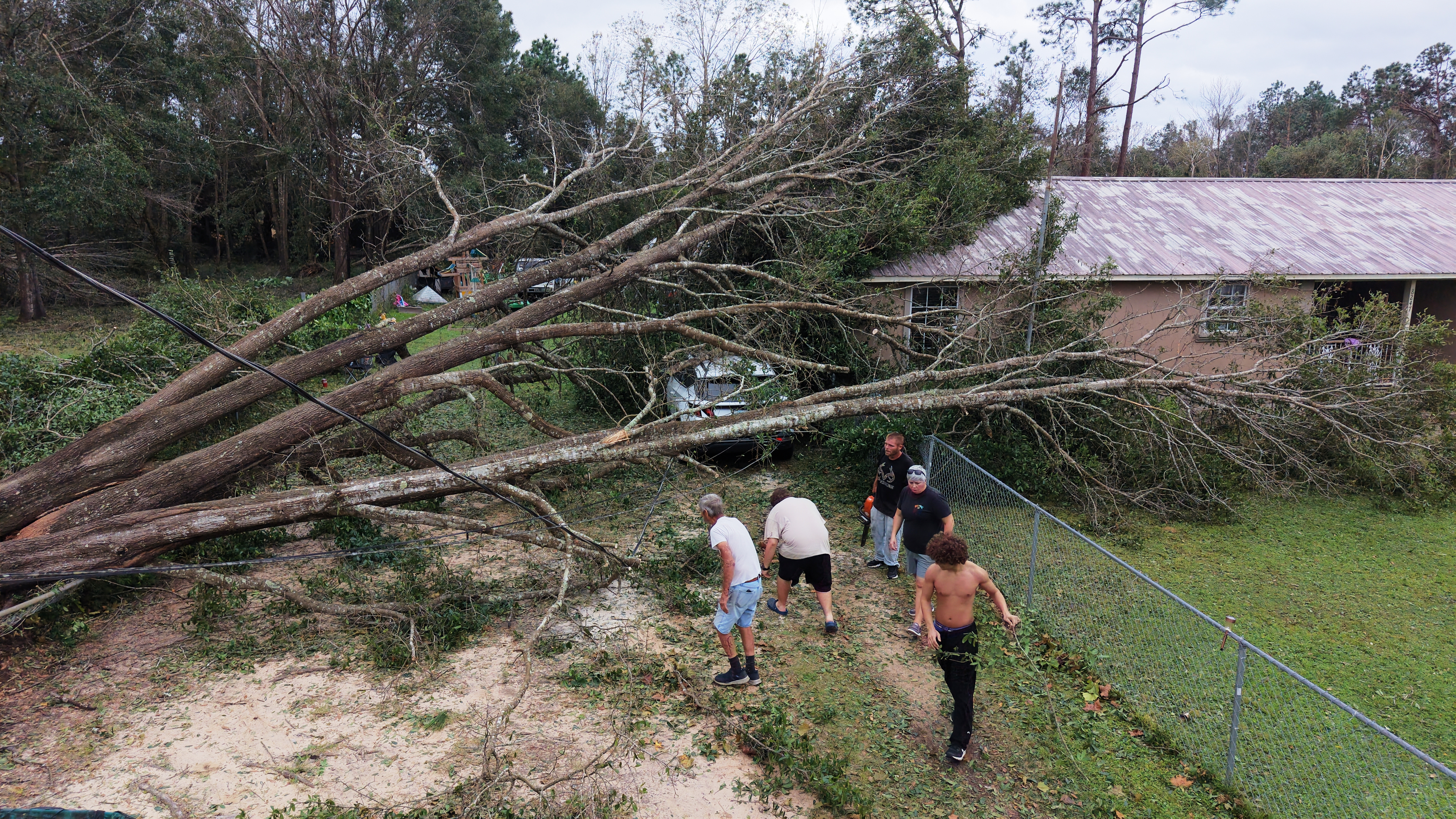 Johnny Ray Wood, and his son Johnny Ray Wood II cut downed trees with other helpers in front of their home in the aftermath of Hurricane Isaias in Milton, Fla., Saturday, Oct. 10, 2026. (AP Photo/Gerald Herbert)
