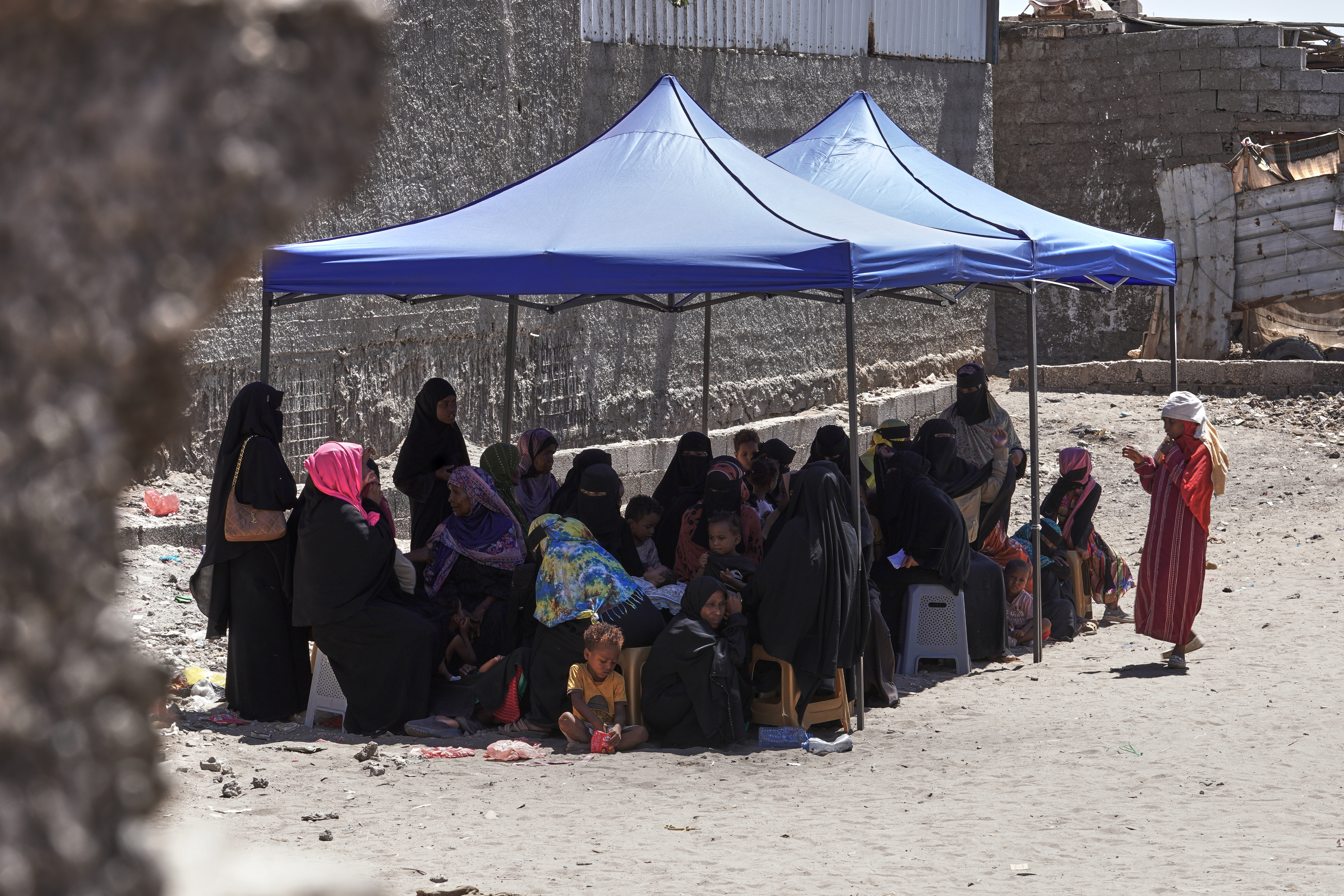 Displaced Yemenis wait in the shade to receive medical treatment provided by Doctors Without Borders (MSF) at the Al-Kod Al-Othmani displacement camp in Sheikh Othman district, Aden, Yemen, Thursday, Oct. 8, 2026. (AP Photo/Abdulnasser Alseddik)