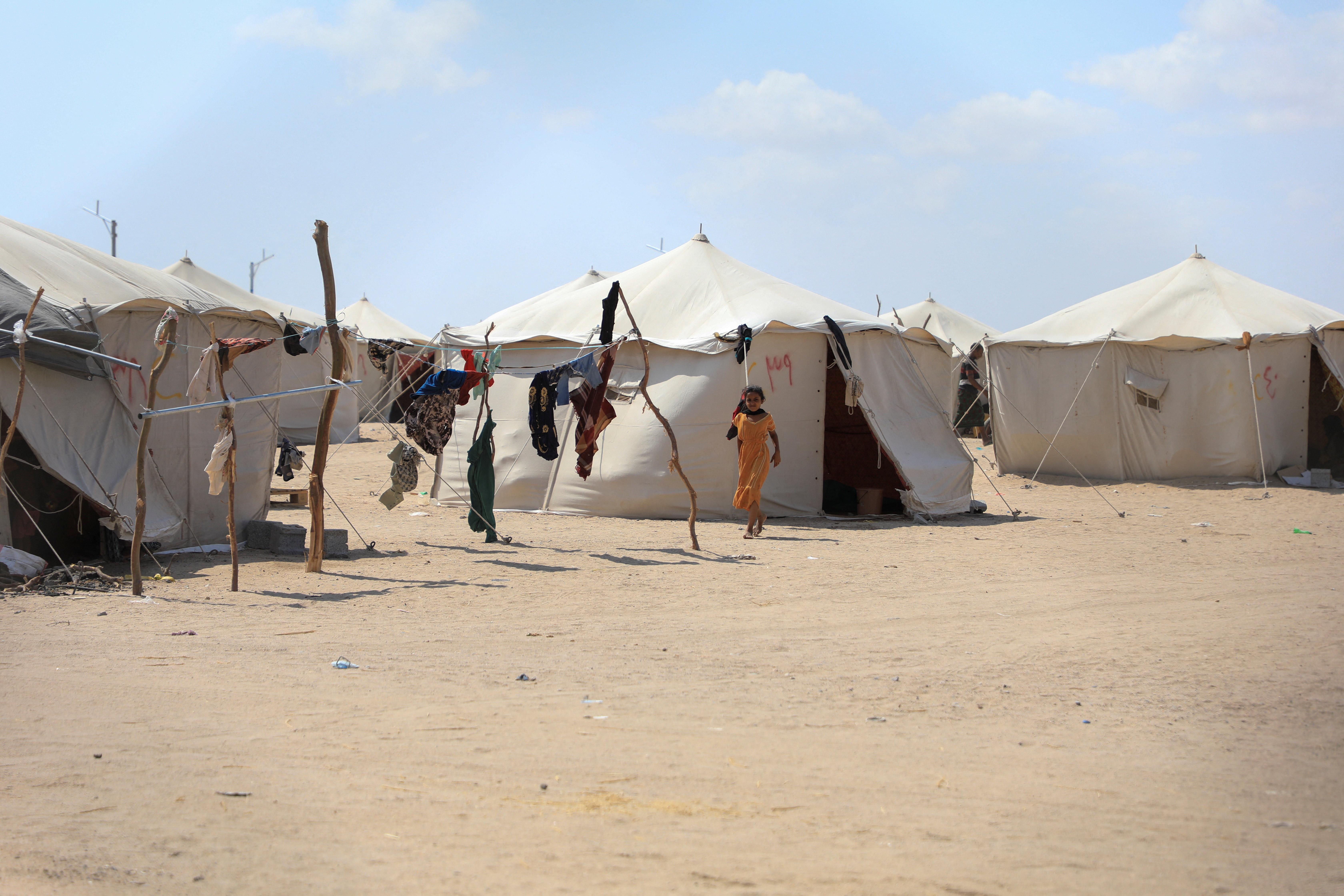 A girl walks past tents in a makeshift camp for people displaced by clashes between Iran-aligned Houthi fighters and Saudi-backed Yemeni government forces, near Aden, Yemen October 7, 2026. REUTERS/Stringer